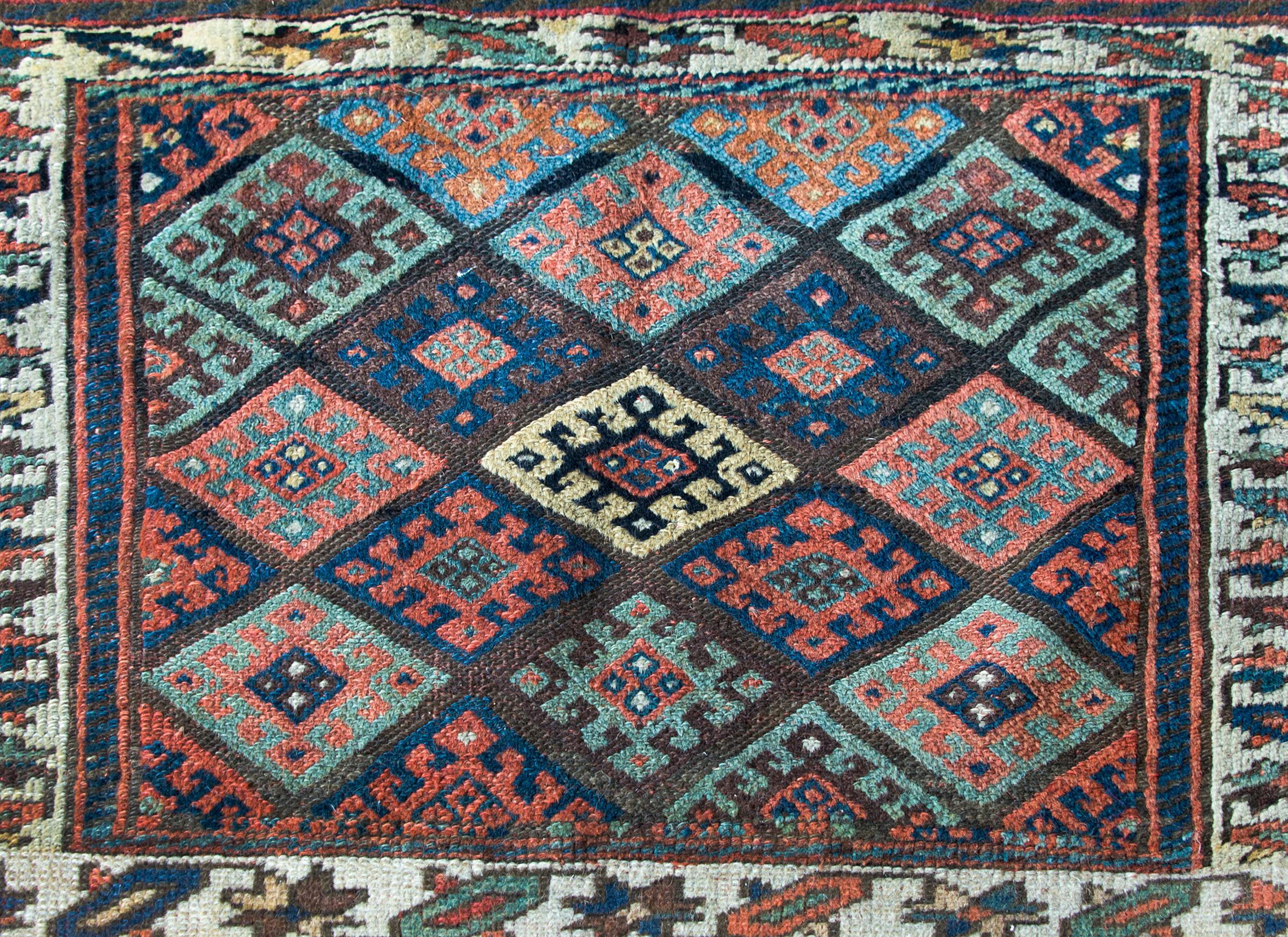 A wonderful early 20th century Kurdish Jaffe rug with a central field with several multi-colored stylized floral patterns, surrounded by a thin border of more stylized flowers, and all woven in crimson, green, indigo, and natural brown wool.