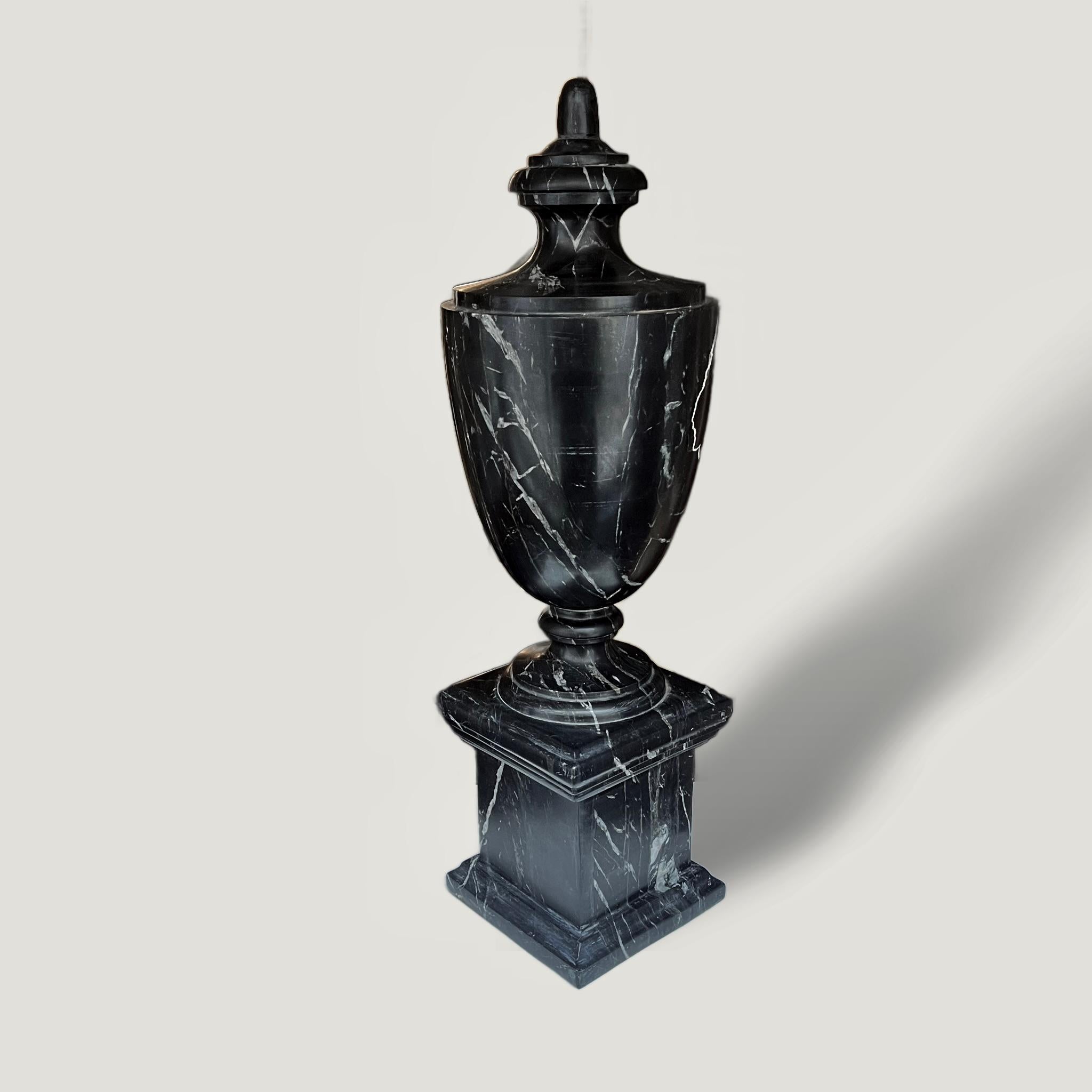 Un'urna decorativa in marmo nero dei primi del Novecento di forma classica posta su un piedistallo. Ricavato da un unico pezzo di pietra di un ricco marmo nero profondo, è contrastato da bellissime striature cristalline bianche.
