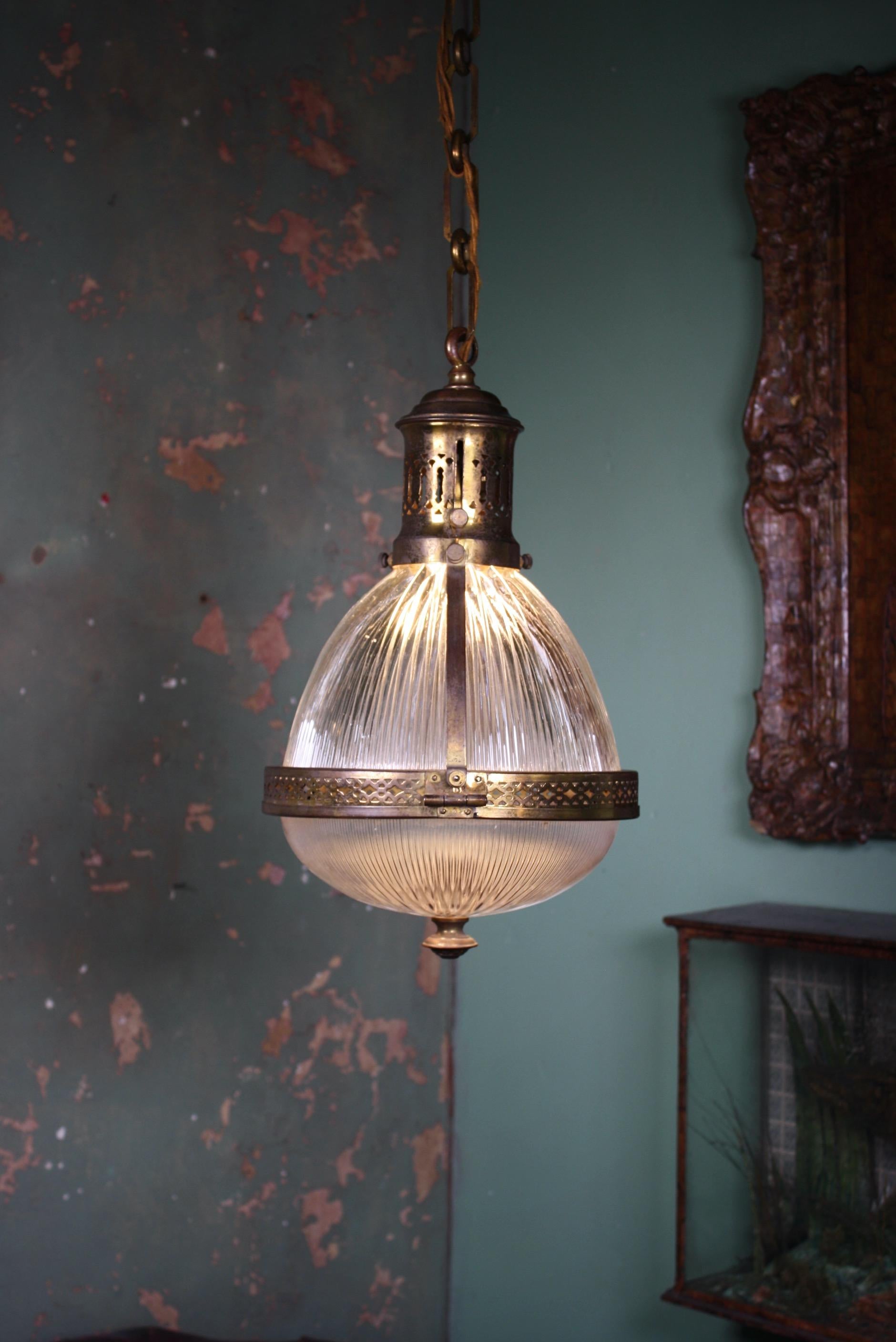 A rare caged French Holophane lantern.

The cage houses two sections of prismatic glass, with decorative pierced central band and gallery. The bottom diffusion plate has a pressed brass finial. 

All metal section have age related oxidization