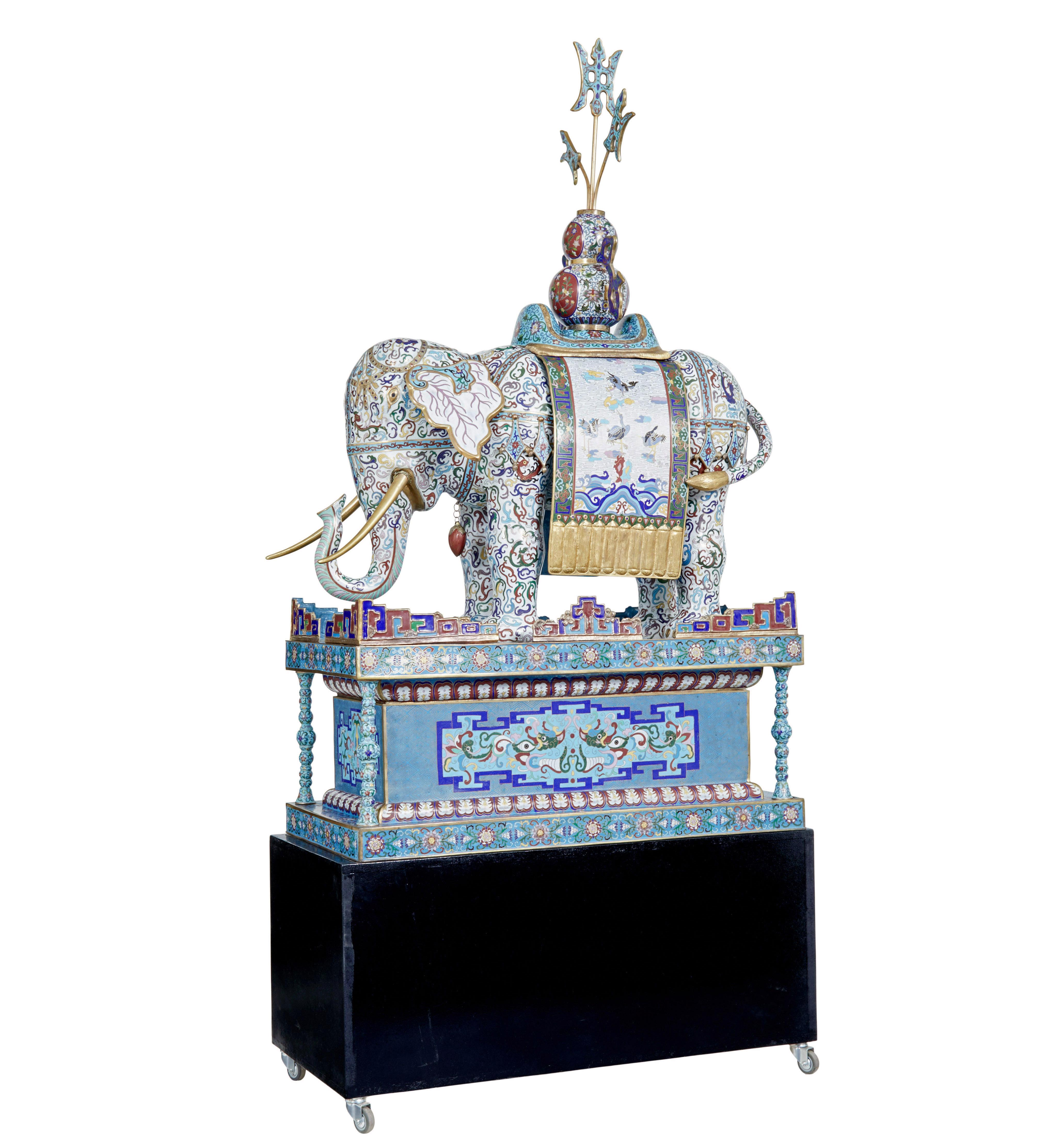 Gran elefante chino de esmalte cloisonné de principios del siglo XX sobre peana, hacia 1900.

Una pieza decorativa realmente rara.

Profusamente esmaltado, modelado portando una silla de montar y remate flamígero.  Con incrustaciones de volutas y