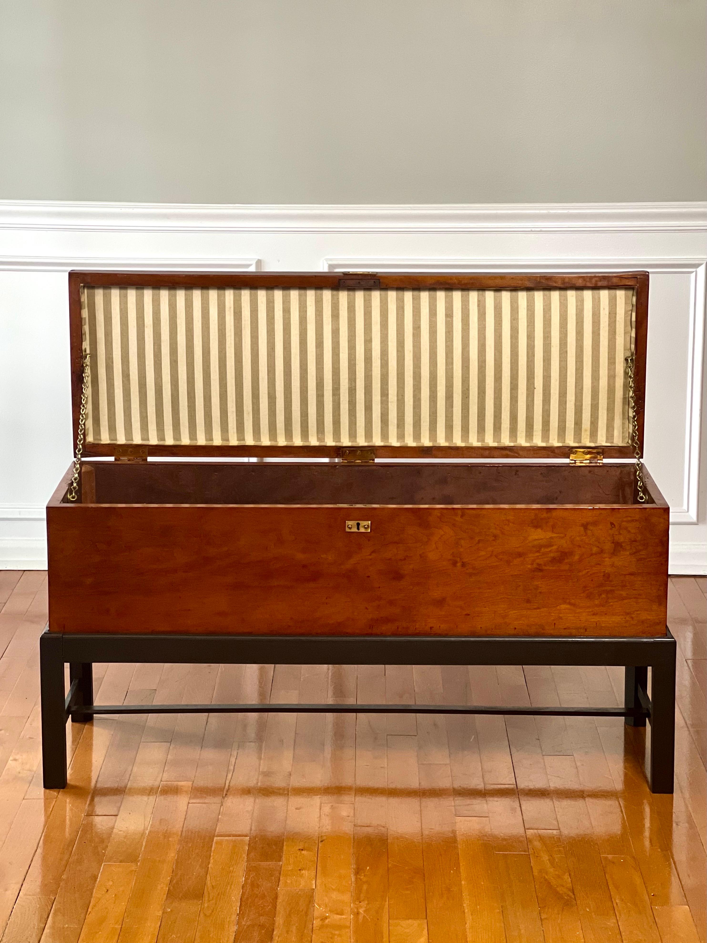 Una grande cassapanca antica in noce su un supporto successivo, circa 1900-1910. Cassapanca rettangolare stretta con coperchio foderato di tappezzeria e sorretto da doppie catene in ottone e maniglie a coda in ottone su entrambi i lati, sollevata su
