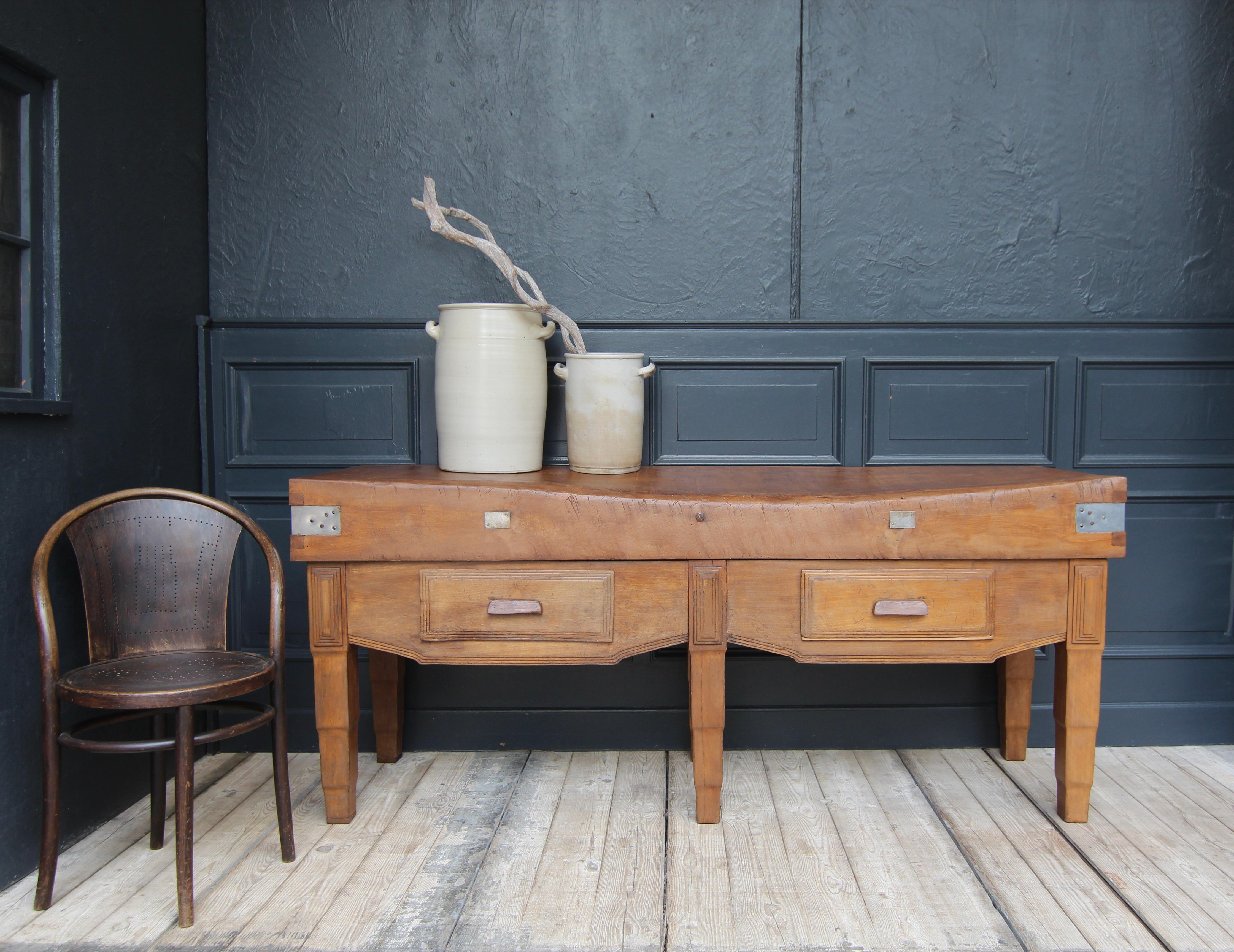 Large French Art Deco butcher's block from the 1920s. Made of solid beech wood. 

The base section stands on 6 slightly stepped square legs with a high frame and 2 large drawers. The solid worktop is up to 20 cm thick.

Since the Middle Ages, the