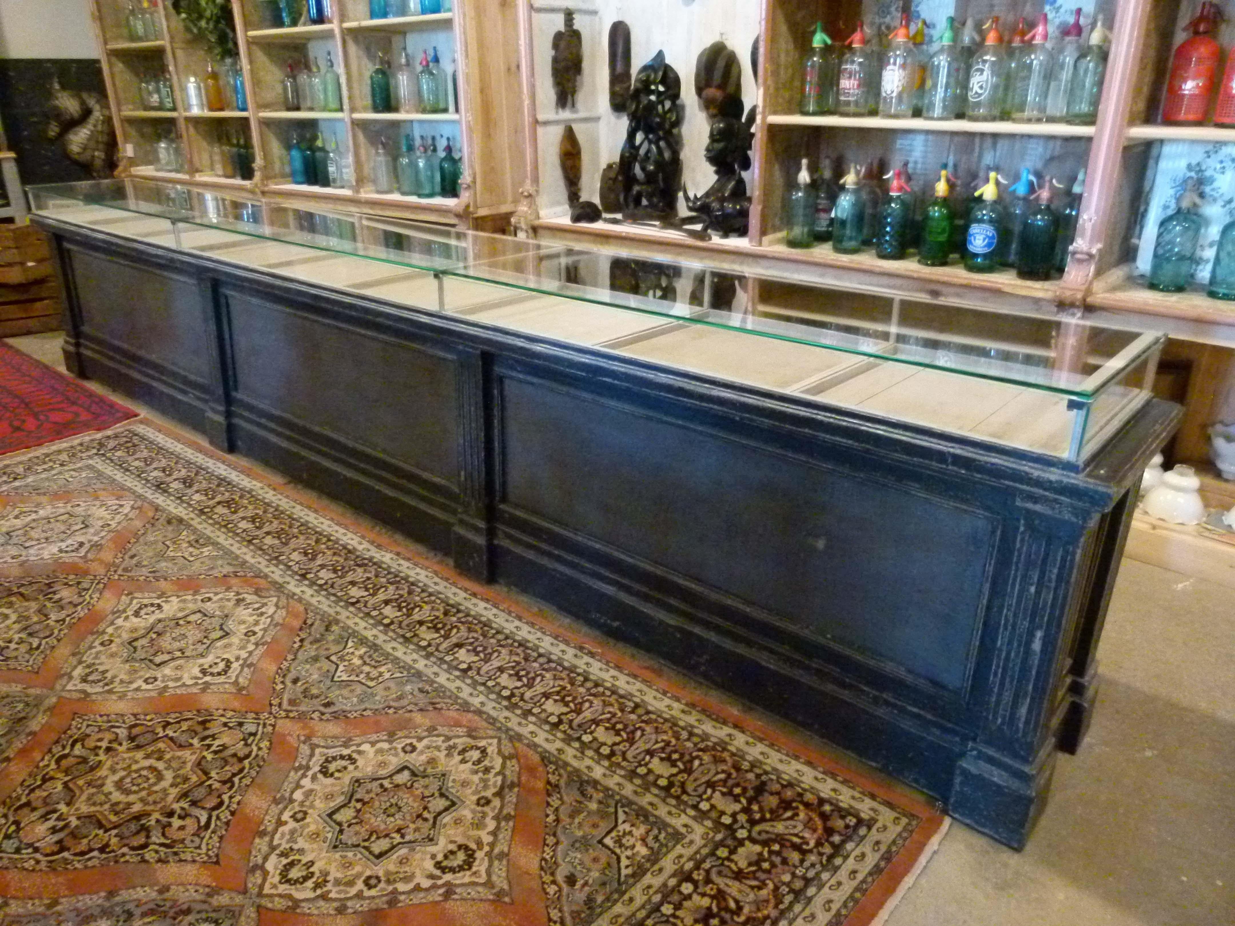 Early 20th century large wood and glass store Counter. It compounds a protective glass on top of 9 sliding display trays and 6 store compartments with folding doors on the interior side.


   