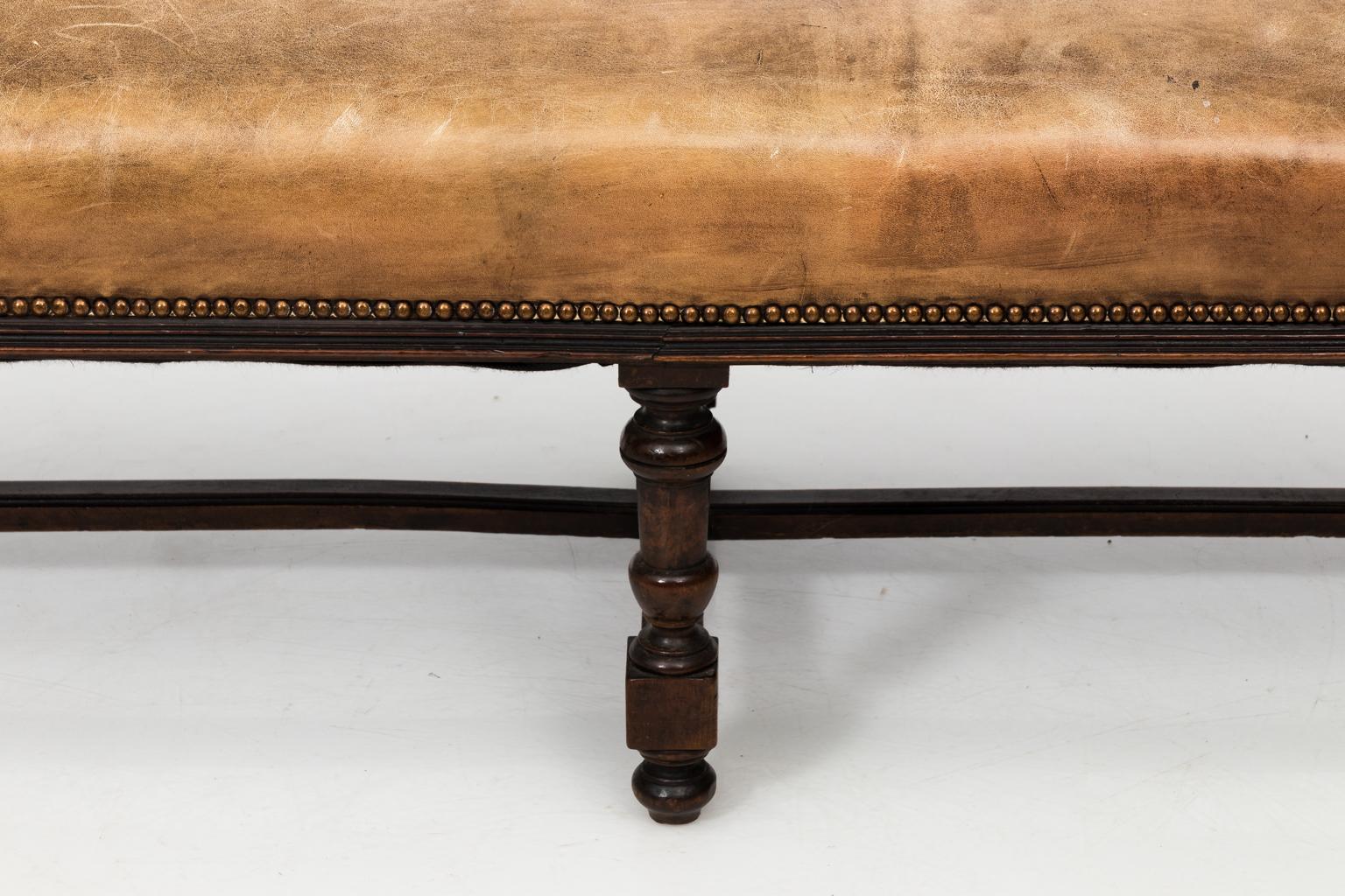 Walnut six-legged bench with cross stretcher and leather covering, circa 1900s.
 