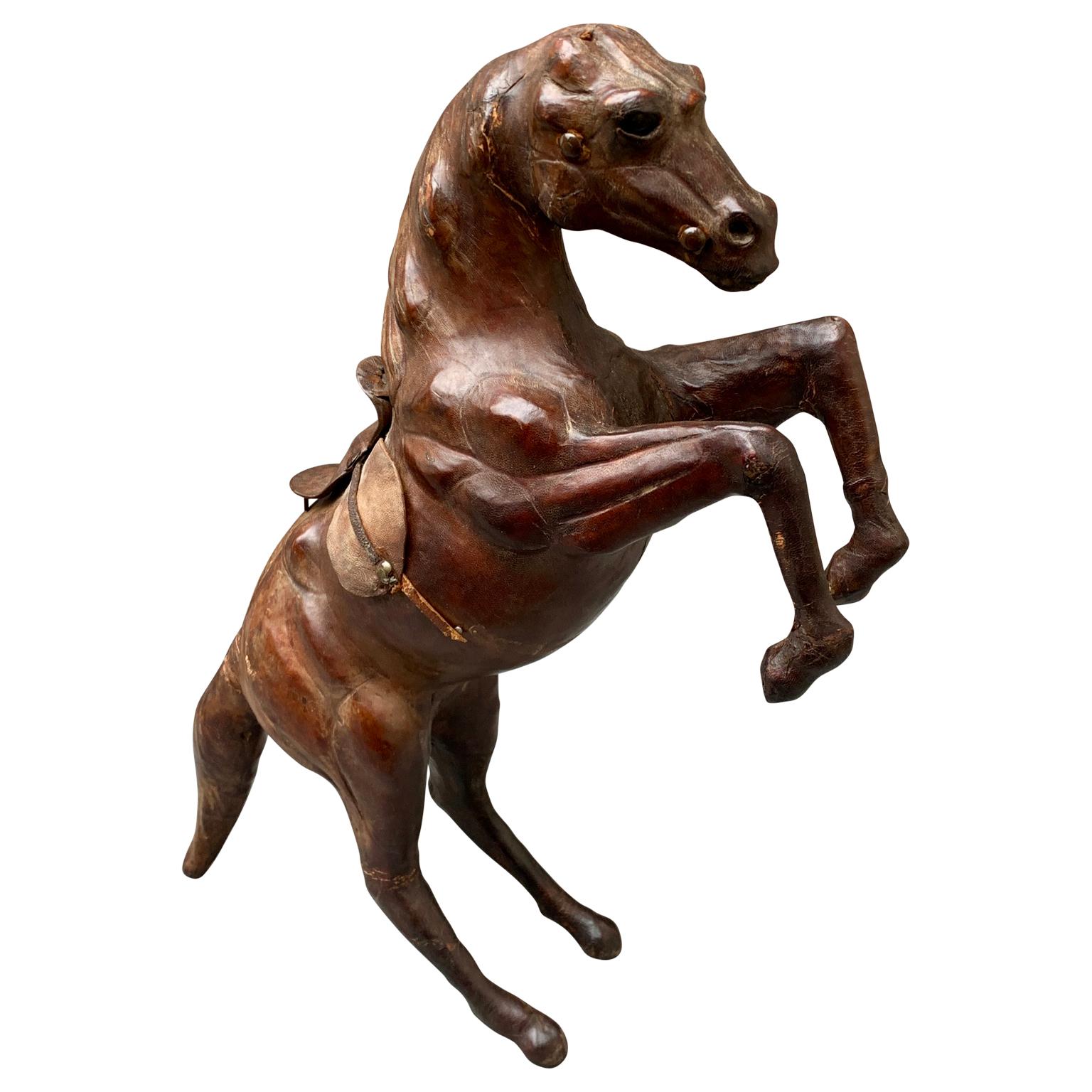An Early 20th Century animal figurative sculpture of a rising horse in leather and papier-maché. This decorative equine figure is standing with the help of its tail. There is quite a bit of detail to this piece, including a handmade leather saddle
