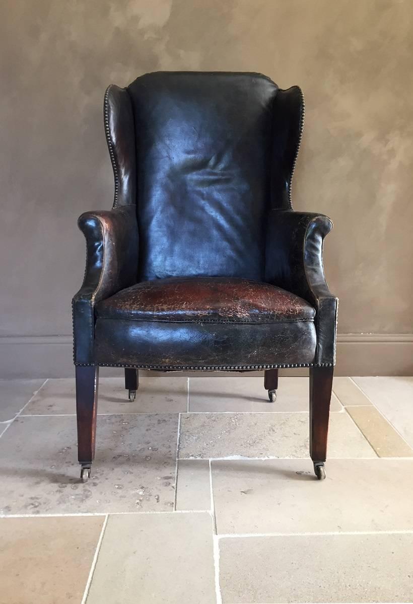 Elegant leather wingchair with mahogany frame, bronze castors and Original upholstery. Probably English and beginning of the 20th century.