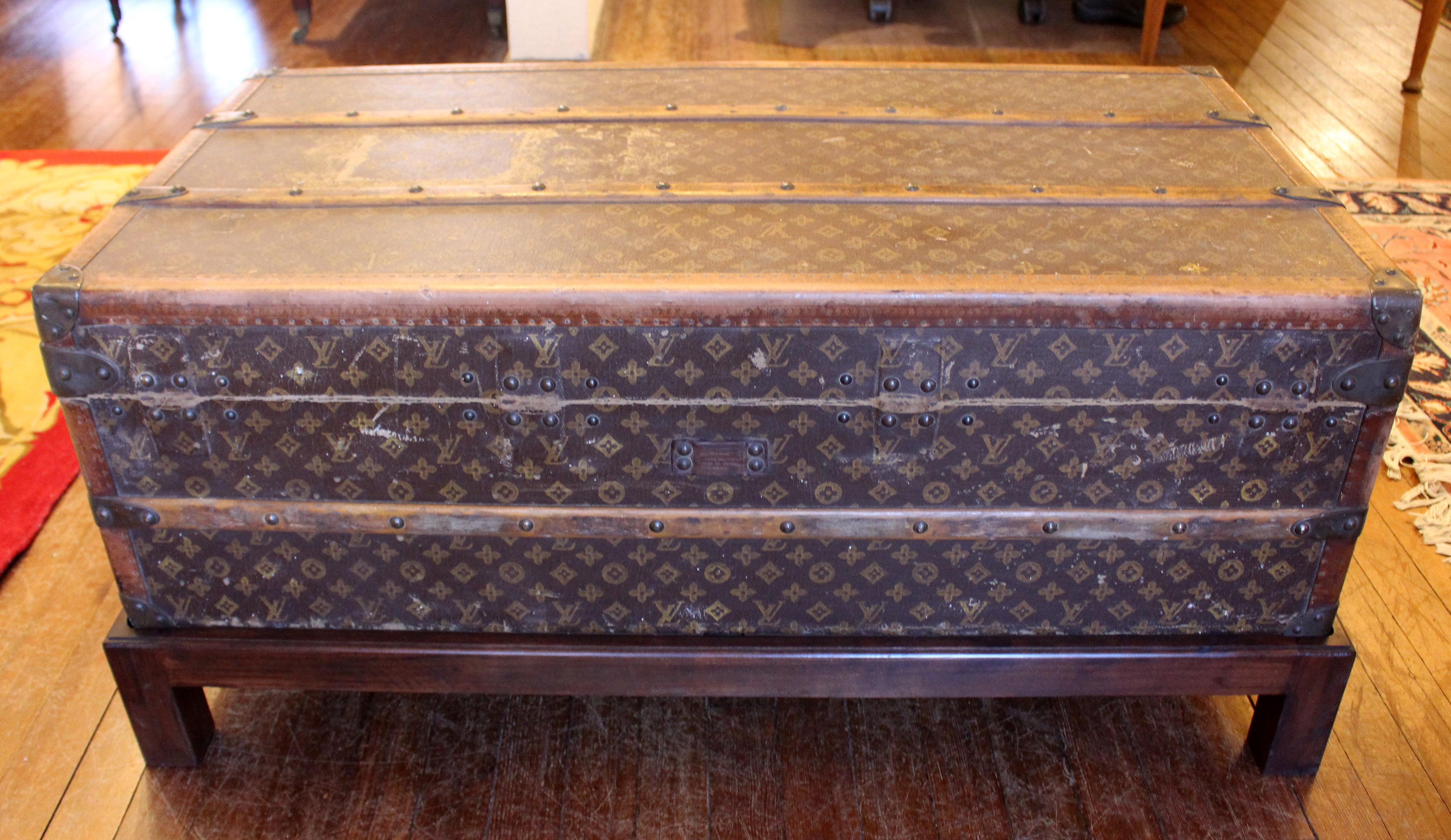 Early 20th century Louis Vuitton travel trunk now on custom made coffee table height stand. Side handles and original casters. LV insignia pattern. Lacks interior tray, however, interior is in remarkable condition. Original labels: 