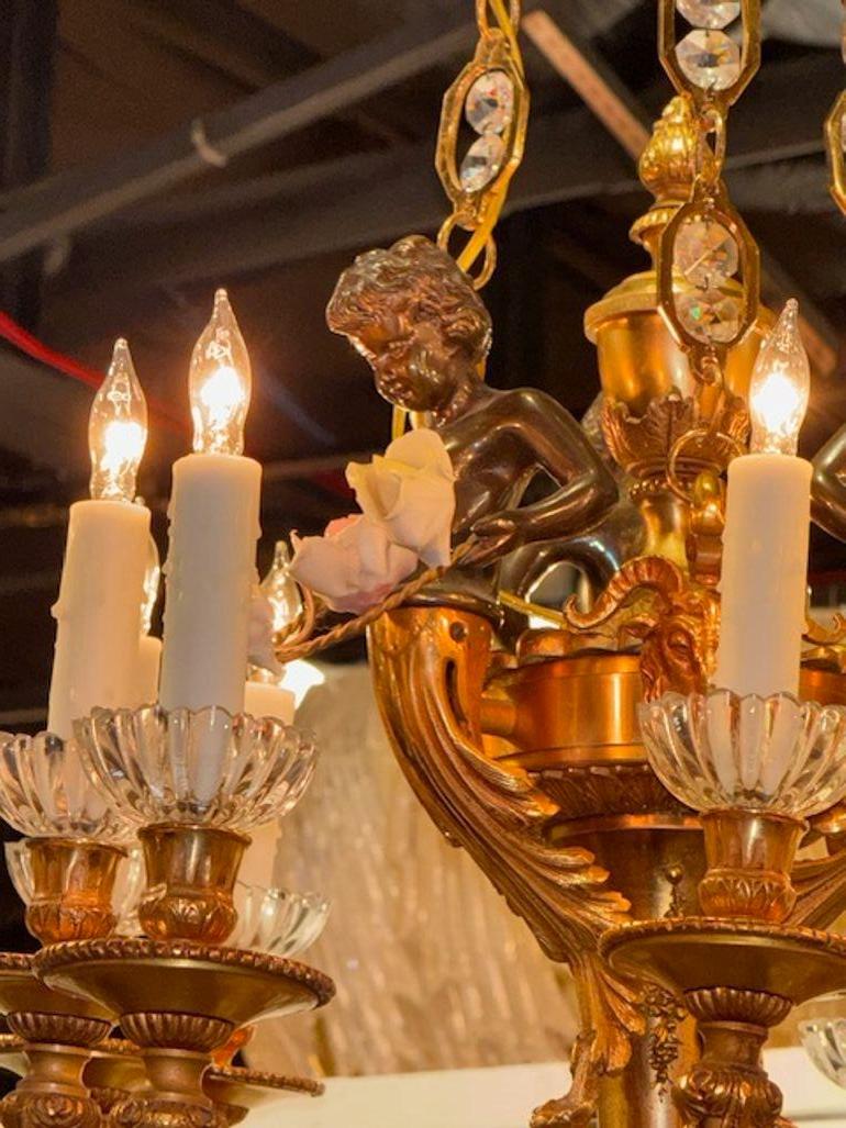 Muy fina, elegante y ornamentada lámpara de araña de bronce dorado y cristal de principios del siglo XX Luis XV con querubines. Esta luminaria emana una sensación de lujo y sofisticación, convirtiéndola en un impresionante punto focal en cualquier