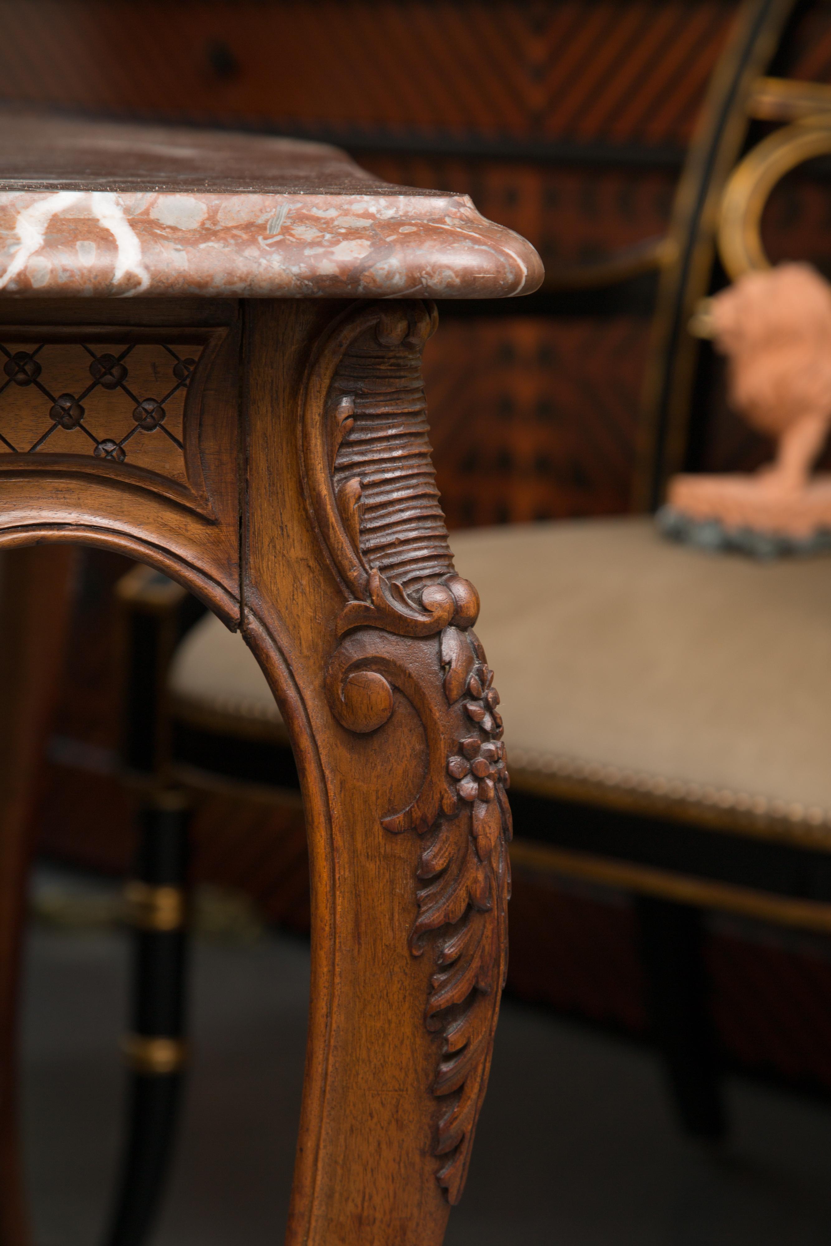 This is a hand carved walnut French Louis XV style centre table with a variegated marble top over an intricately carved and shaped frieze. The table is supported by graceful cabriole legs joined by a curving X-stretcher centred by carved basket of