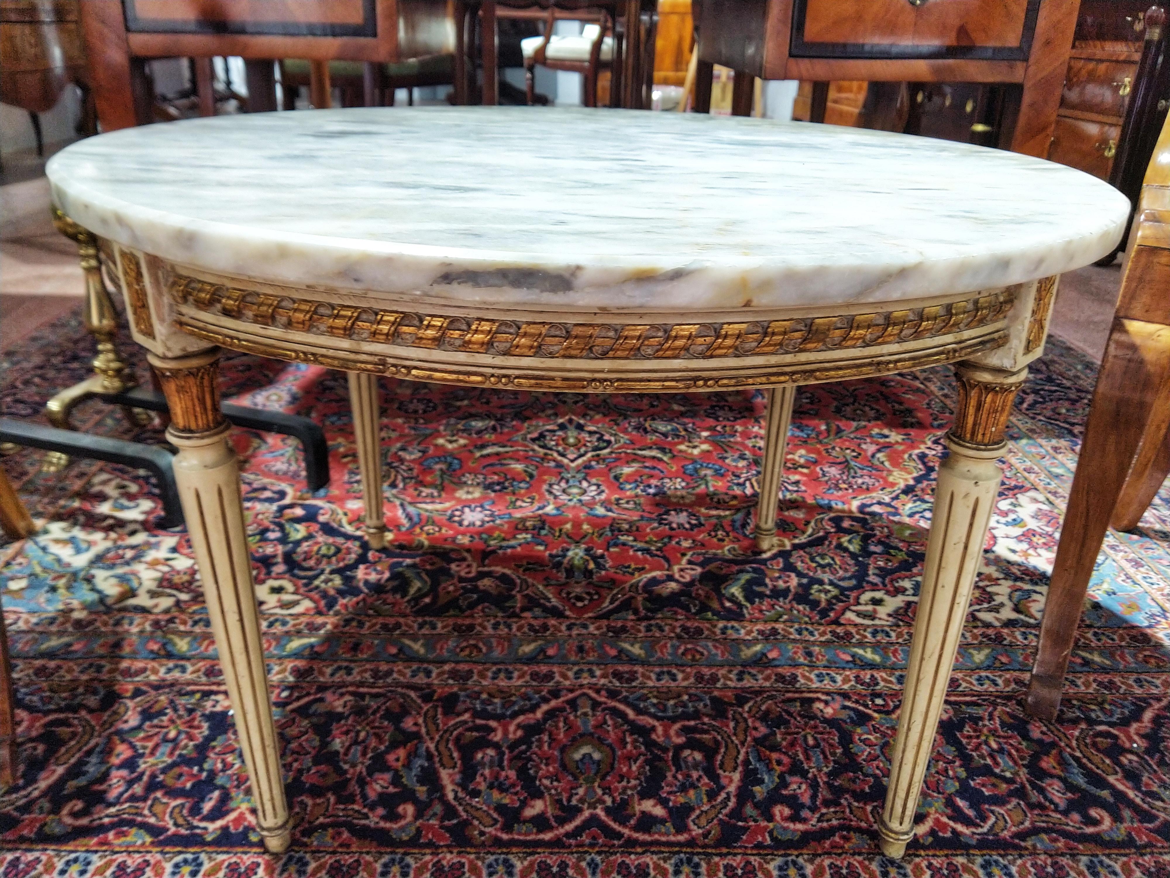 Beautiful Louis XVI style low center table. The wood is colored, carved and gilded, the top of Italian marble Calacatta Fabbricotti stands out for its white color with gray and gold veins giving it a further regal touch. A very elegant and tasteful