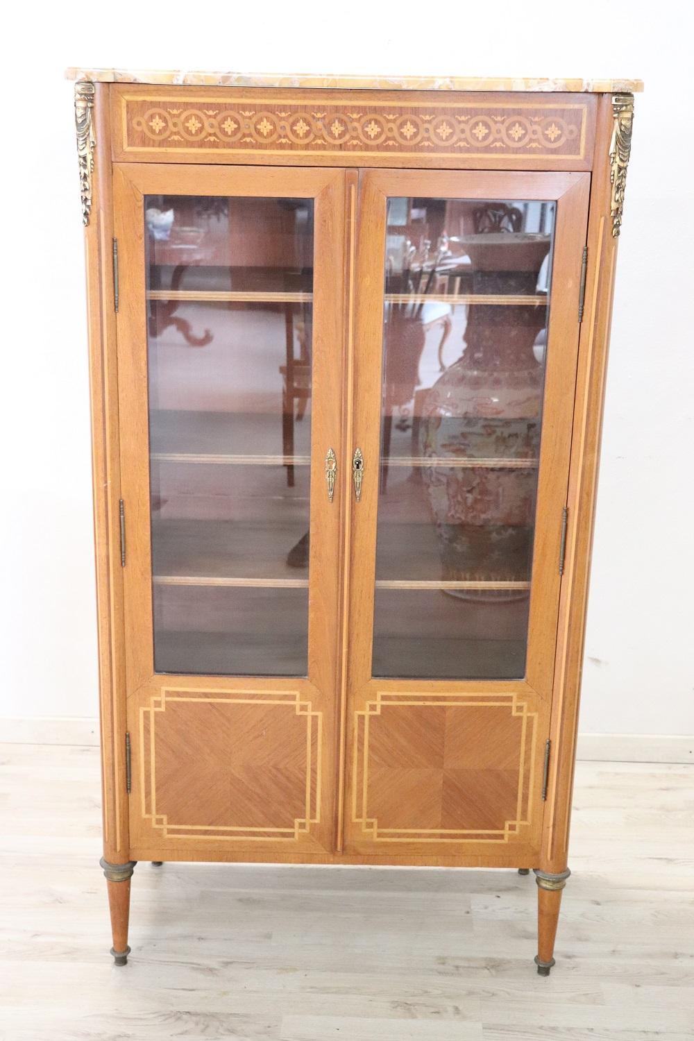 Elegant Louis XVI style vitrine characterized by finely inlaid walnut. Enriched with precious finely chiseled golden bronzes. Refined and rare yellow marble top. Internally four shelves that can be moved to the desired height. Perfect for displaying