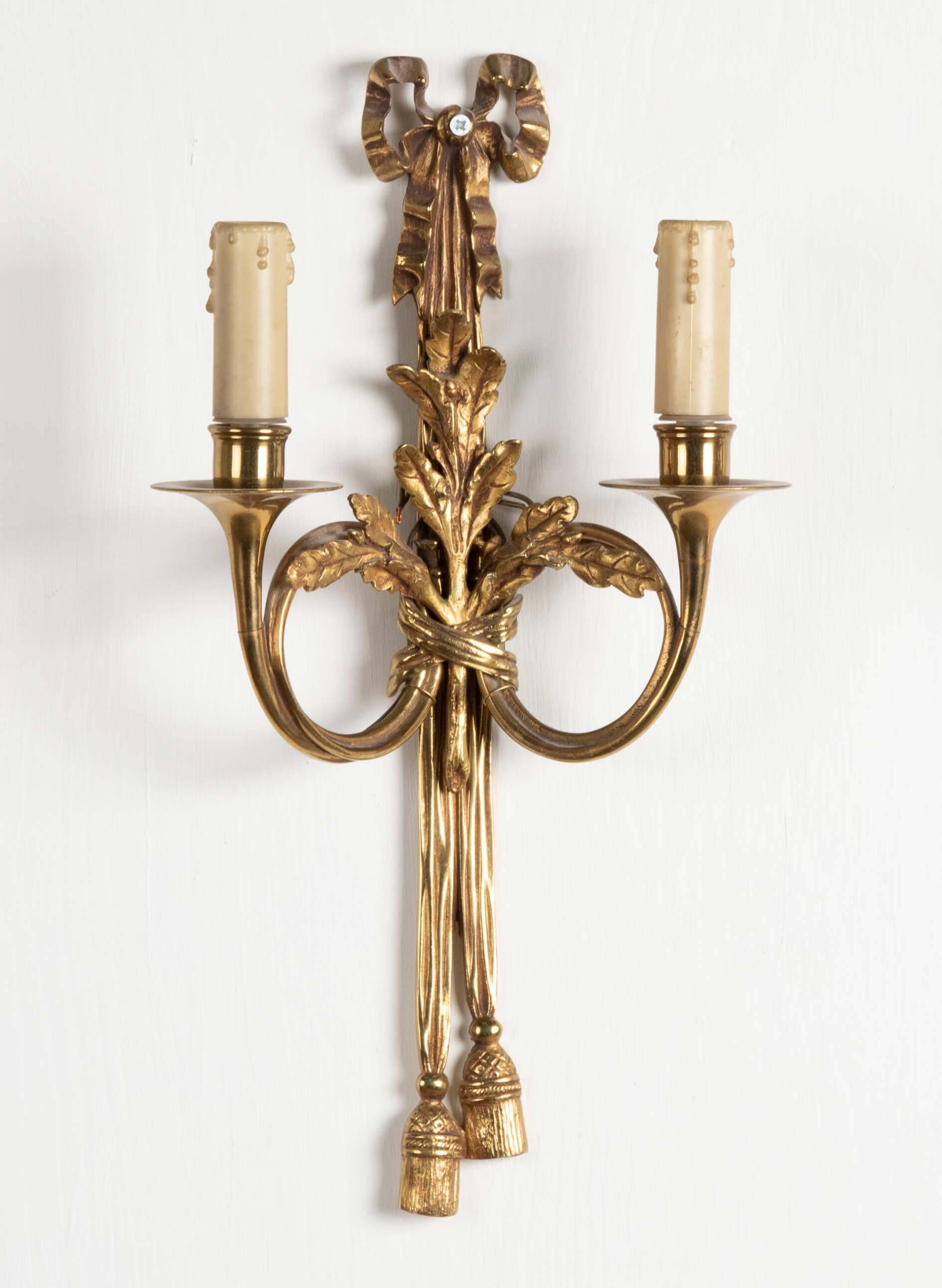 Pair of Louis XVI style gilt bronze wall lights with two light branches, in the matter of Claude Galle. Decorated with ribbon bows, lace trimmings and oak tree branches, both light branches shaped as horns. This wall lamps are made in France, about