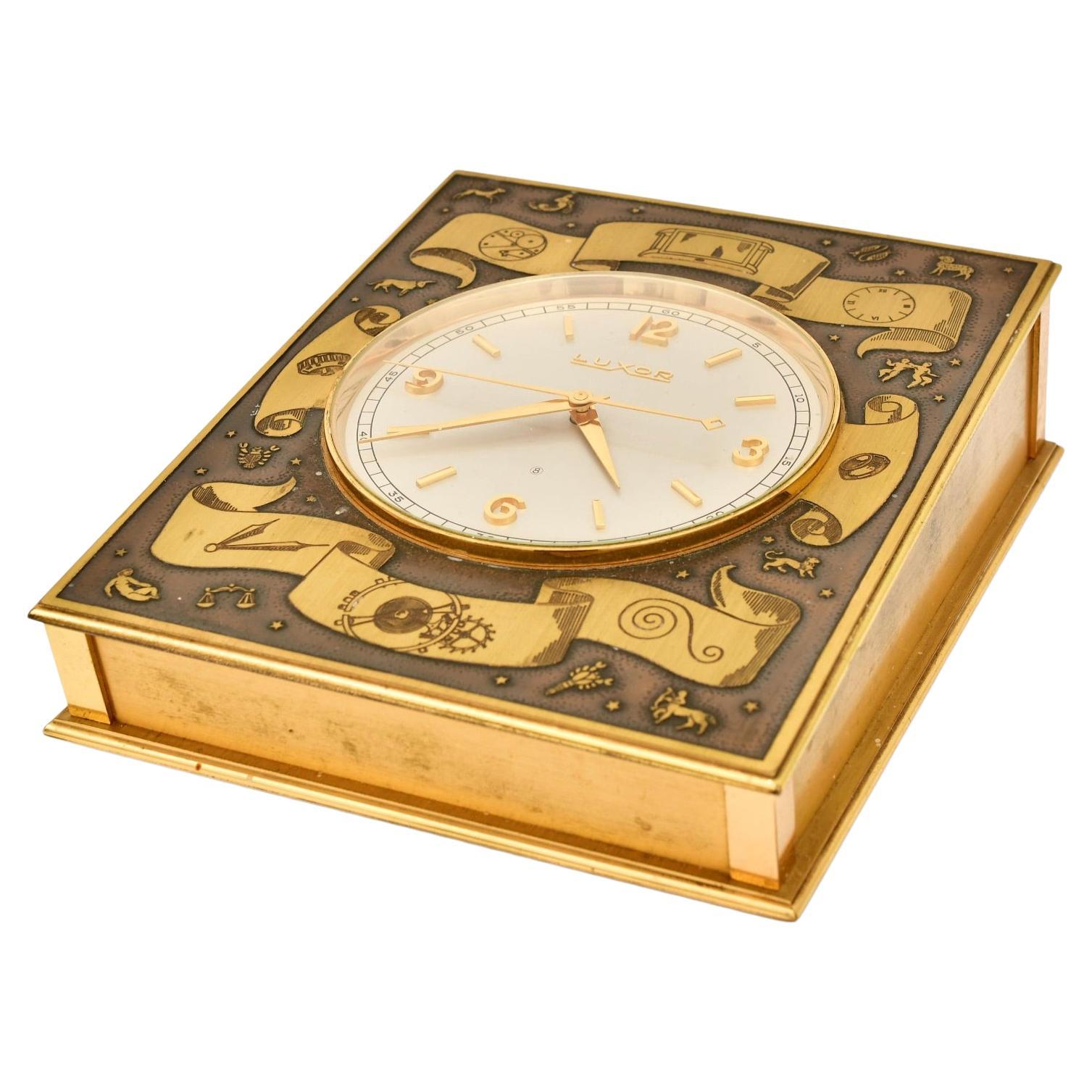 An exceptional early 20th century gilt-bronze desk or table clock by Luxor of Switzerland, showcasing both horological precision and decorative artistry. The rectangular case is finely cast in gilt brass, embellished with intricate astrological and