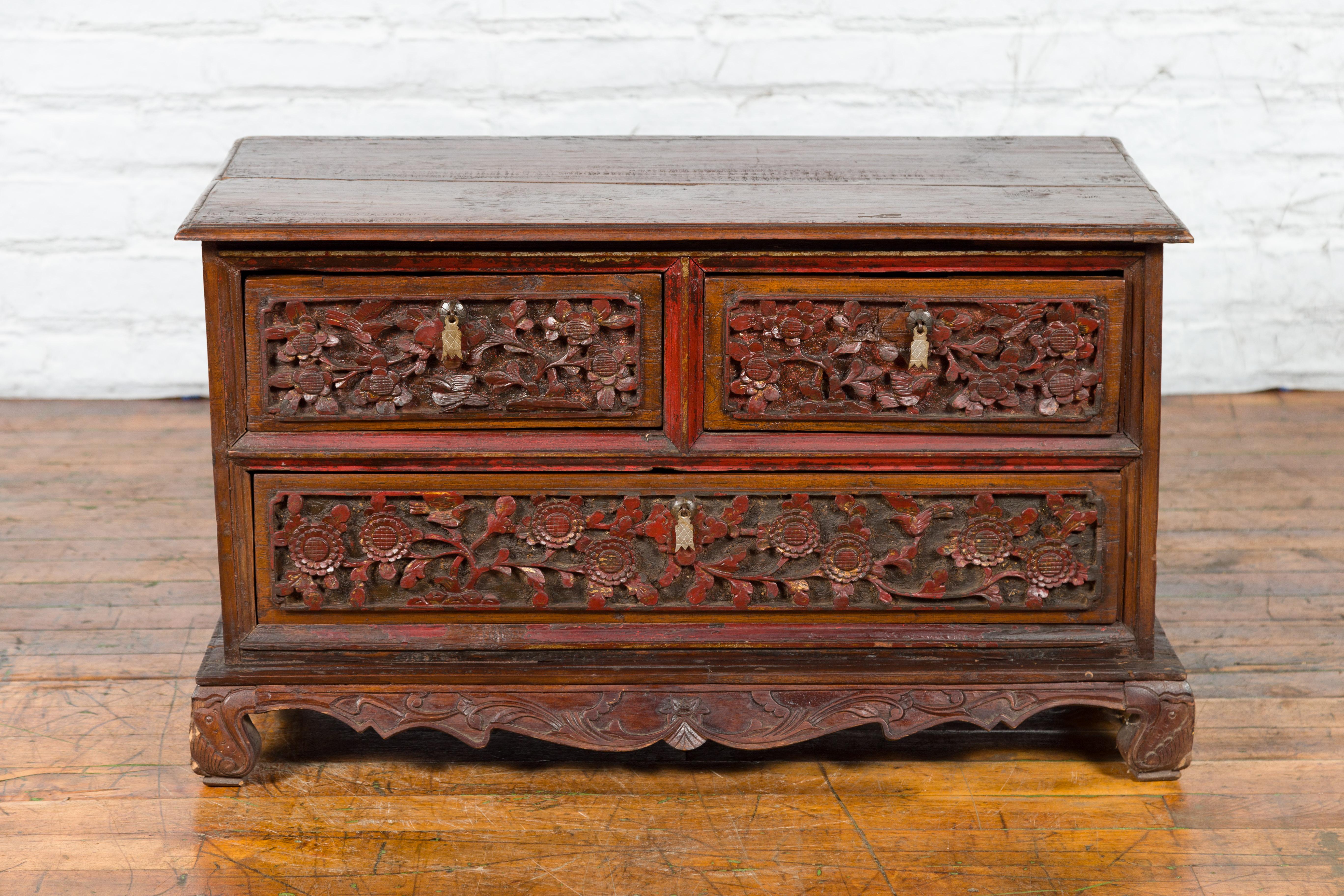 An antique Indonesian floral hand-carved wooden treasure chest from the early 20th century, with iron handles. Created on the island of Madura off of the northeastern coast of Java, this treasure chest features a rectangular planked top with beveled