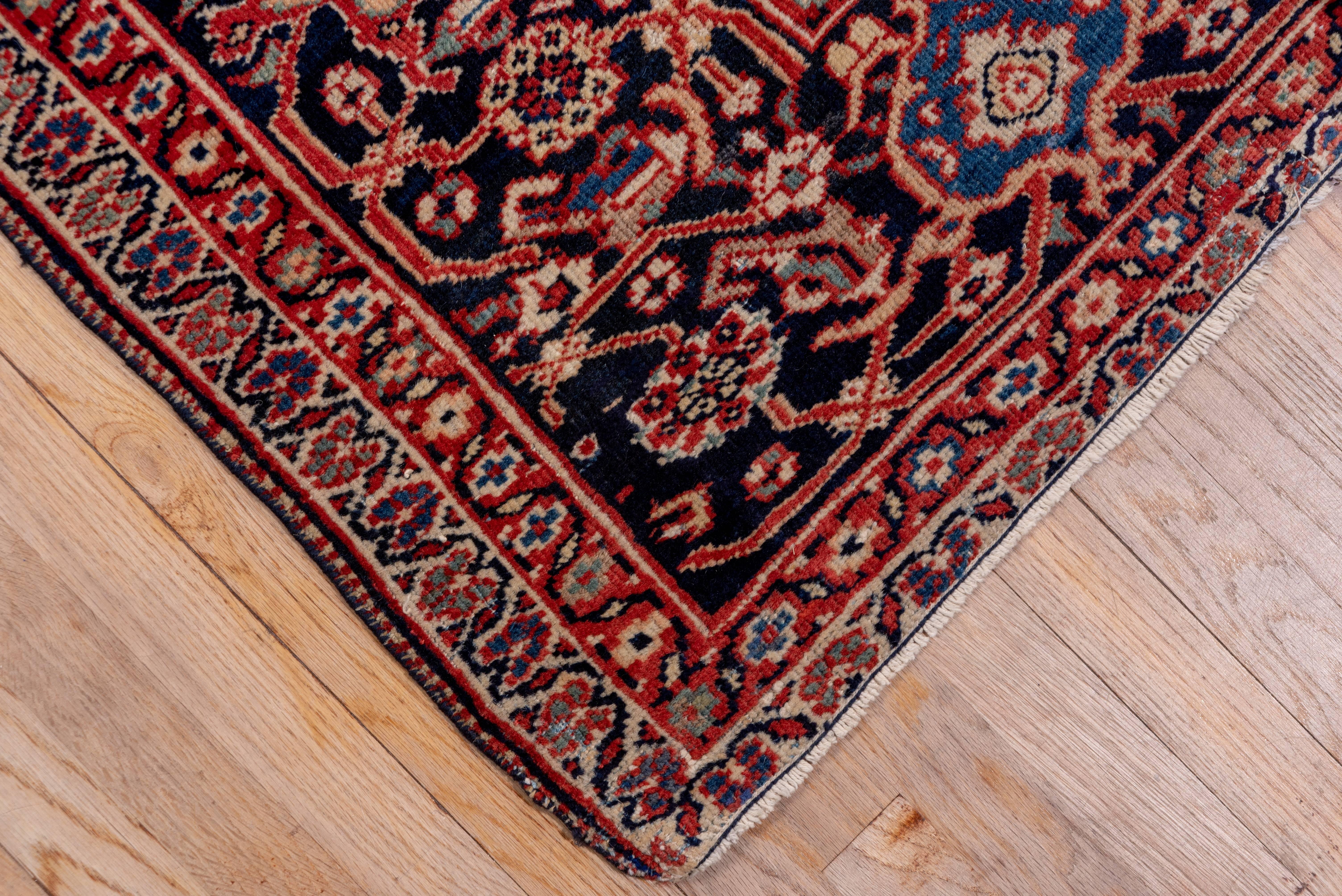 This high quality west Persian village carpet displays a good madder red field with an allover pattern of green lozenges and bars, eight palmette radiating arrays and lobed ivory small medallions. The blue-black border shows well-drawn turtle