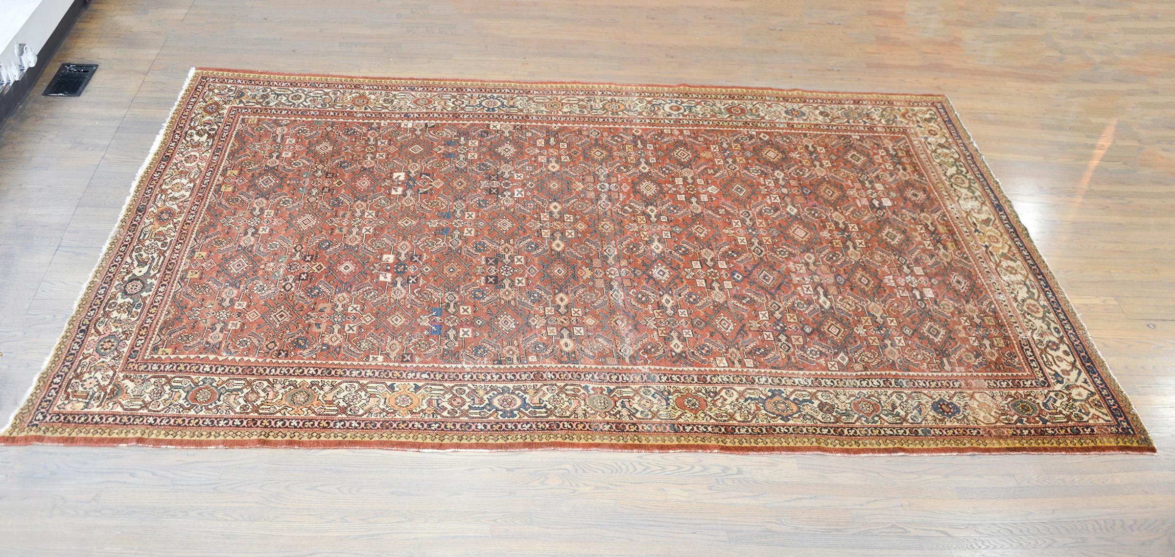 An incredible early 20th century Persian Mahal rug with an all-over floral trellis pattern woven in beautiful muted reds, blues, greens, and golds, set against a burnt orange background, and surrounded by a wide floral and scrolling vine partnered