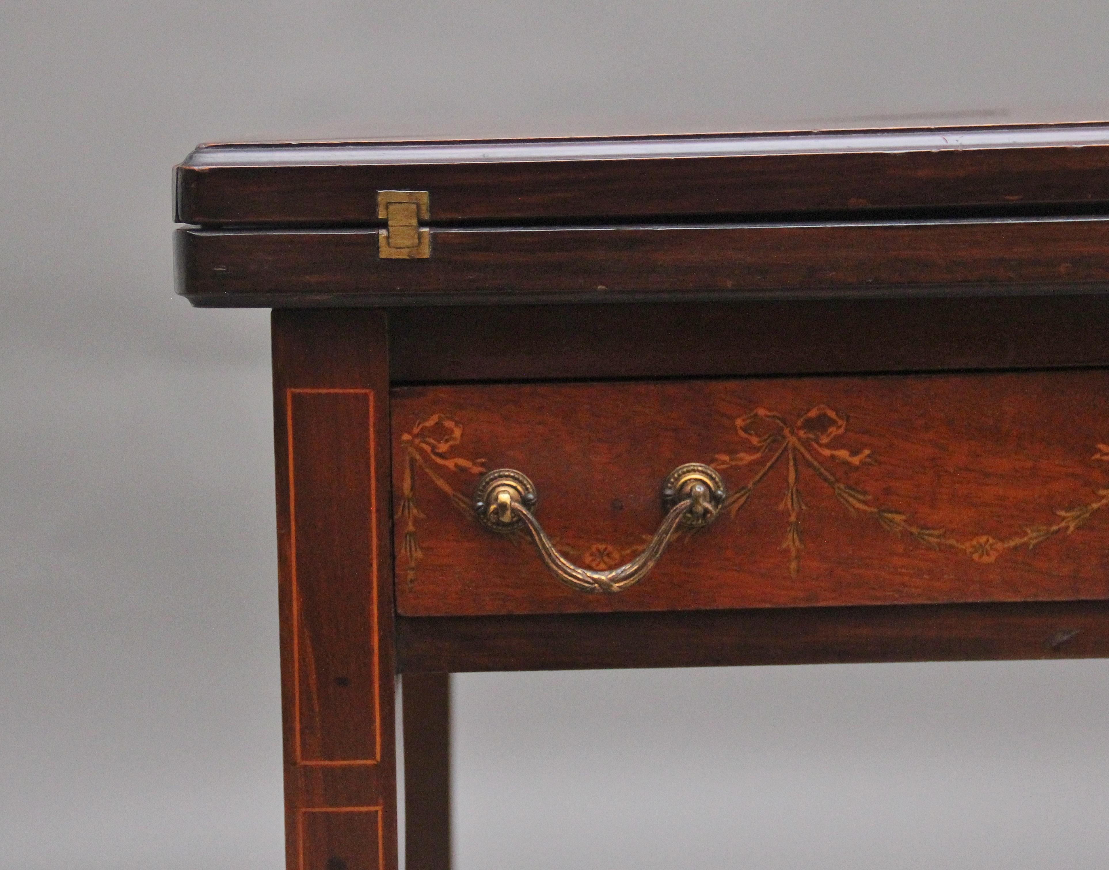 Early 20th Century mahogany and inlaid card table, having a wonderfully inlaid top with decorative floral and boxwood inlay, the four flaps turn over to reveal a brown baize lined playing surface, having a mahogany lined frieze drawer below with the
