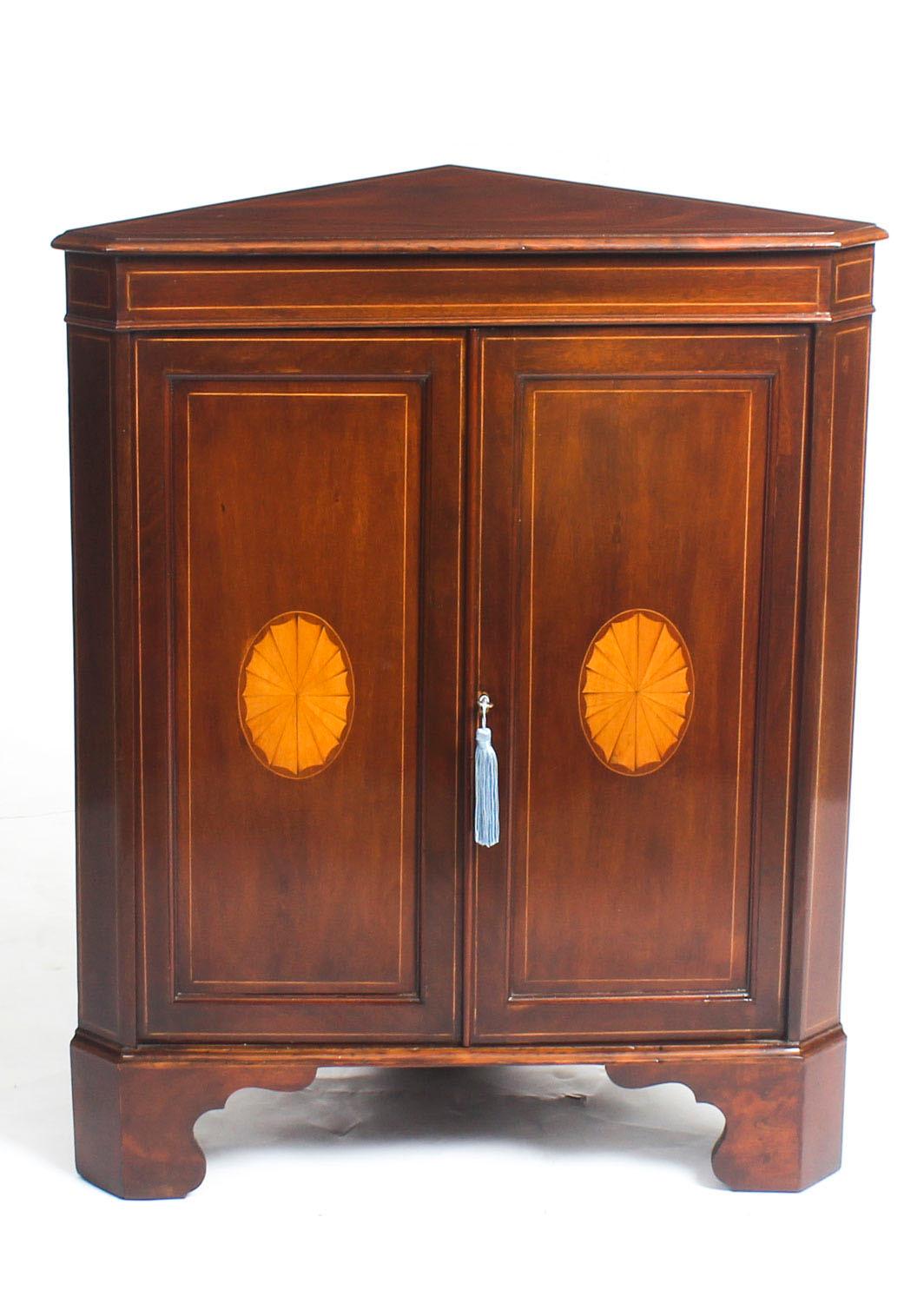 This is a fabulous antique Edwardian English Mahogany and Satinwood inlaid low corner cabinet, circa 1900 in date.

The cabinet is inlaid with a pair of satinwood fans and features boxwood stringing on the panelled doors which open to reveal a