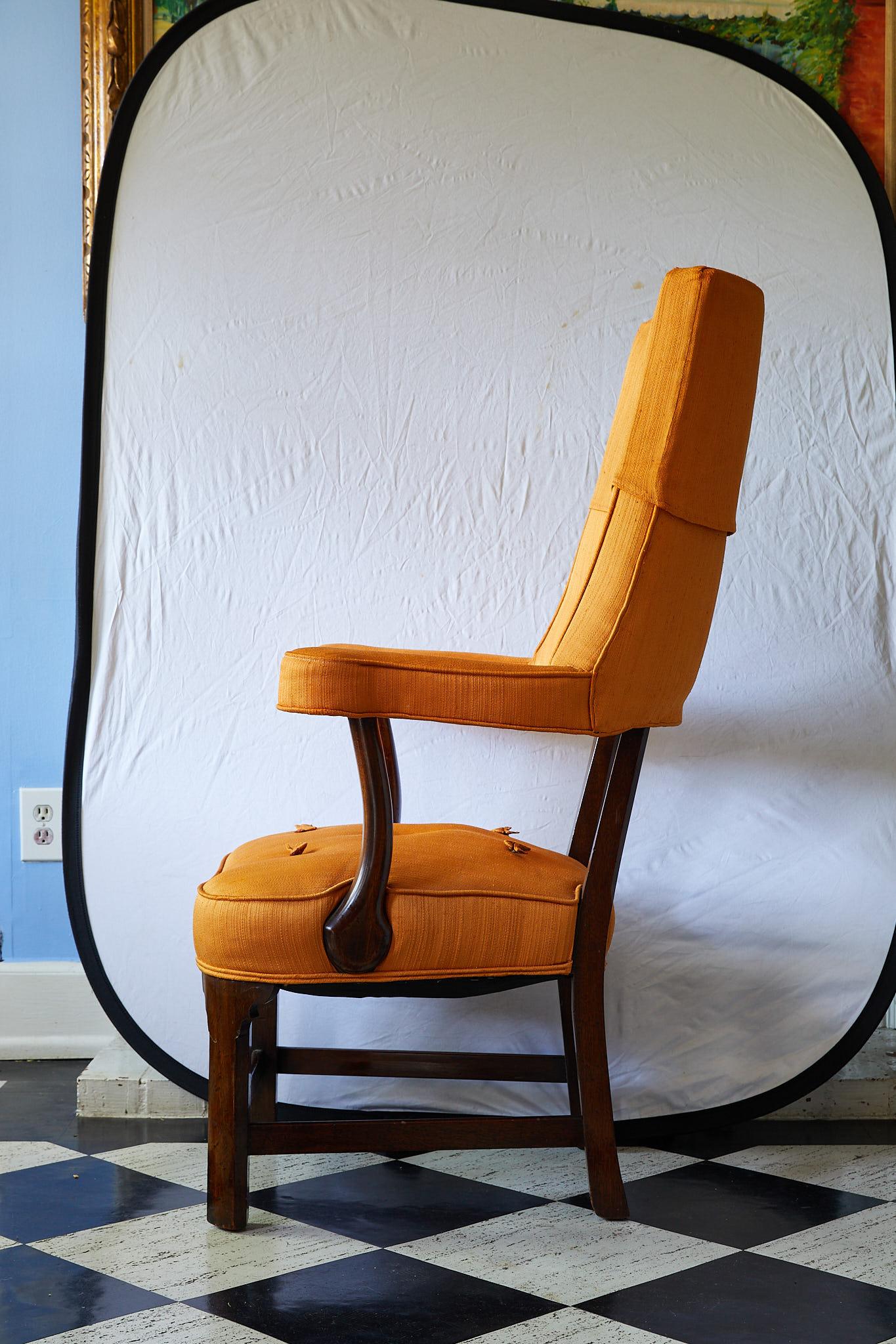 Early 20th century armchair made of solid mahogany and having an upholstered back, arms, and seat in a vintage orange fabric with ribbon tufting.