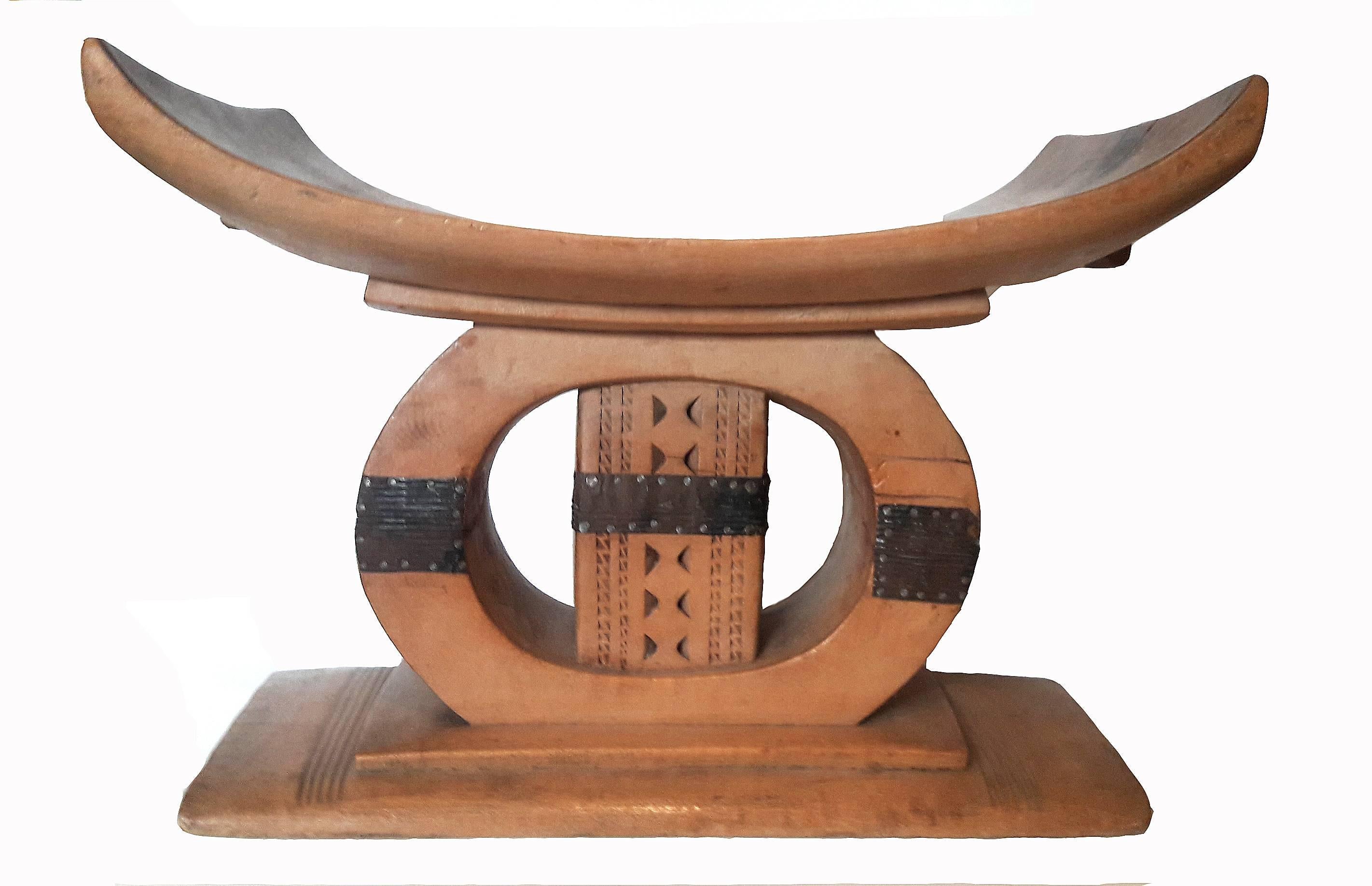 A vintage Ashanti stool from Ghana, hand-carved from a single piece of African mahogany, circa 1920. Traditional decorations. Metal bands. A singular piece that can be used as a low side table, or as an eye-catching element, adding an eclectic look