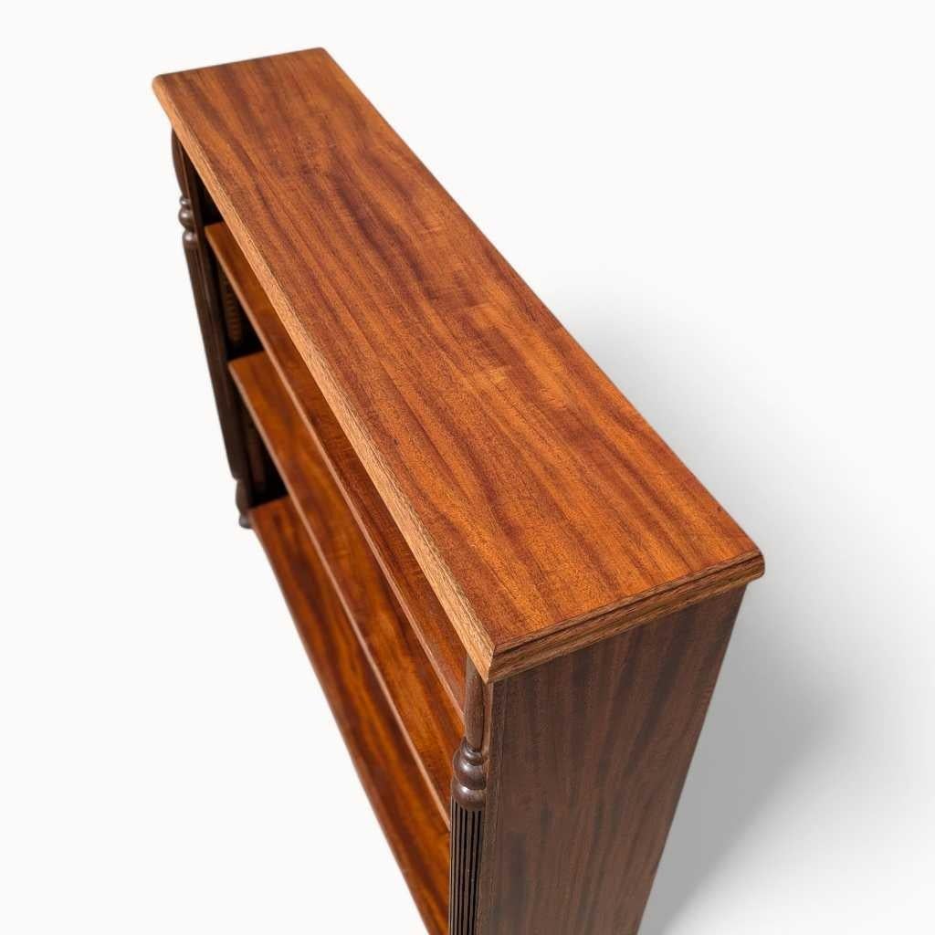 Cette bibliothèque en acajou du début du 20e siècle est finement travaillée et présente un riche placage en grain de ruban ainsi que des colonnes élégamment tournées.

Cette pièce reflète le raffinement du design édouardien et Coloni, avec un
