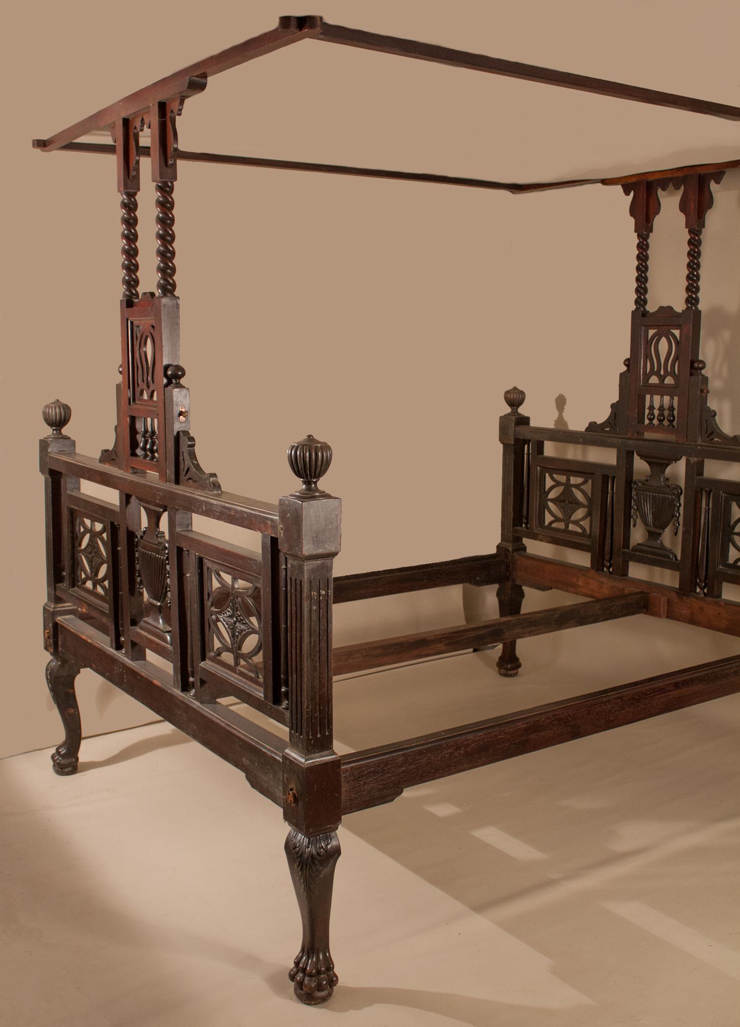 This circa 1900 hand-carved mahogany tester bed is a treasure from Kolkata, once the capital of British India. The head- and footboards are mirror images, with Grecian urns carved in the center  and panes with carved flowers on both sides. The