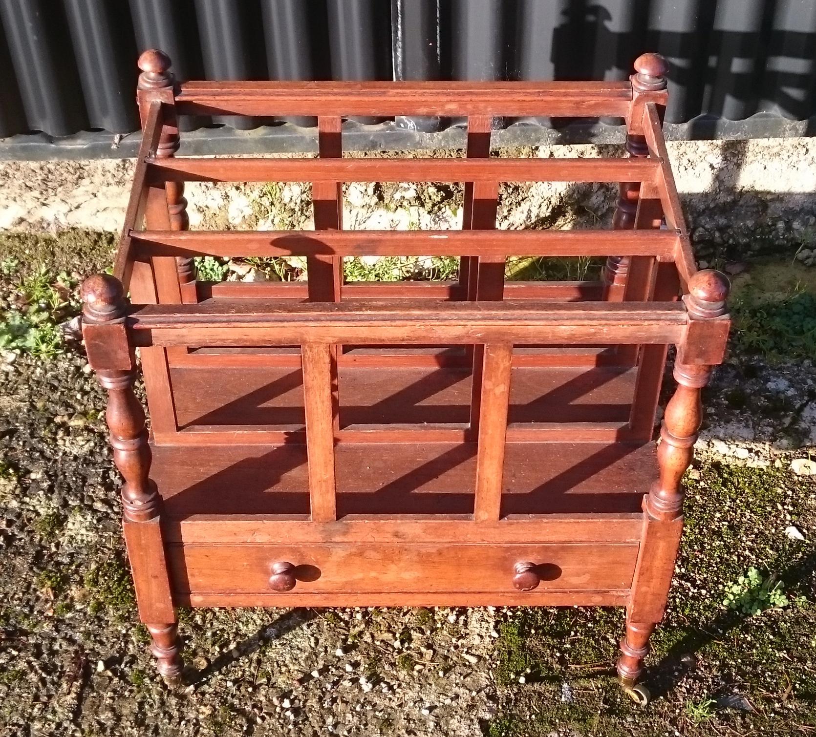 Very fine quality 1920s mahogany Canterbury made by Howard and Sons. This magazine rack is very well made with mahogany lined drawers and precision dovetails. The turned detail to the legs, spindles and handles is very fine and the casters are very