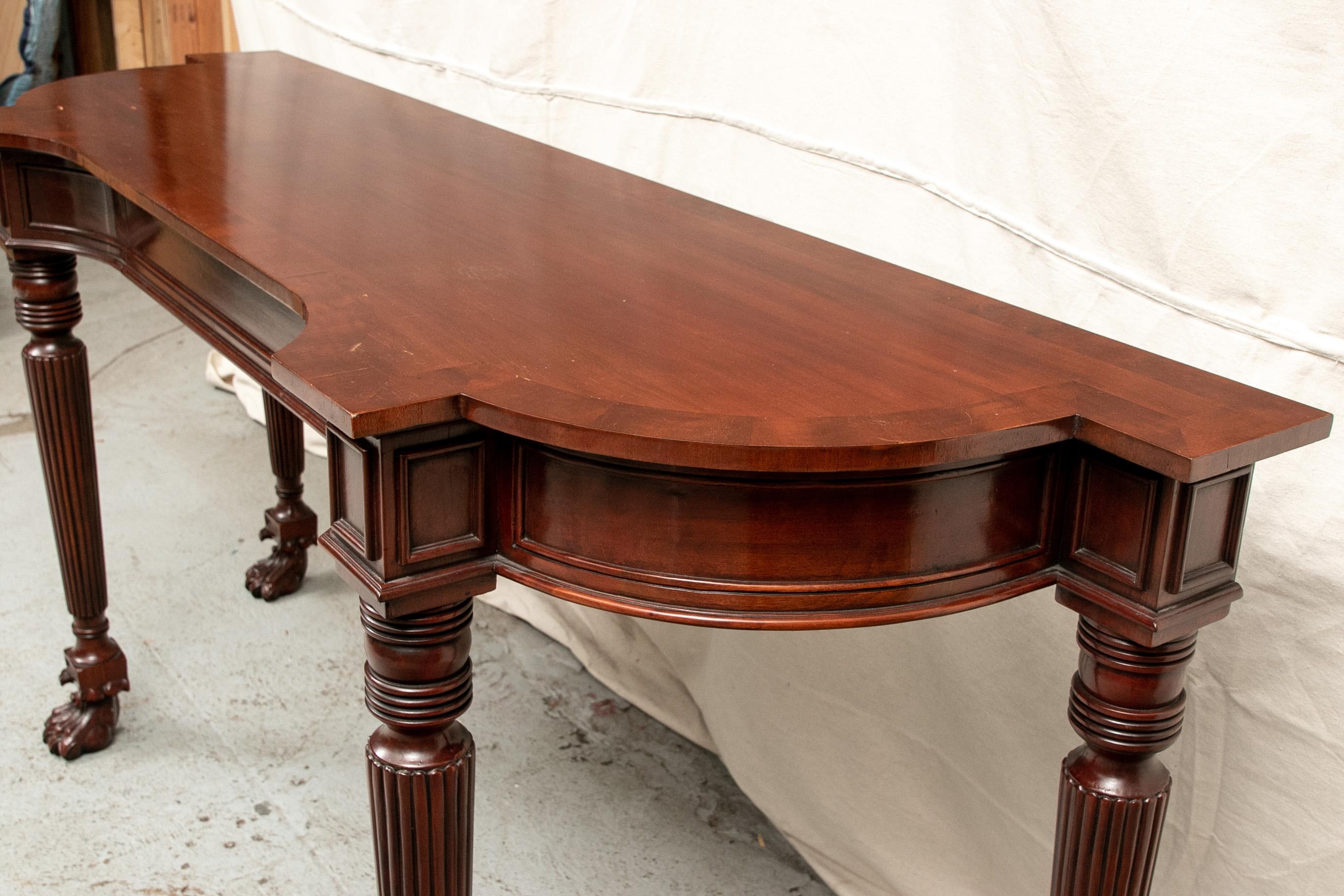 Early 20th century console table, circa 1940, mahogany, shaped demilune top over single central drawer and supported on turned and reeded cylindrical legs ending in intricately carved paw feet.

Condition: expected signs of use including some