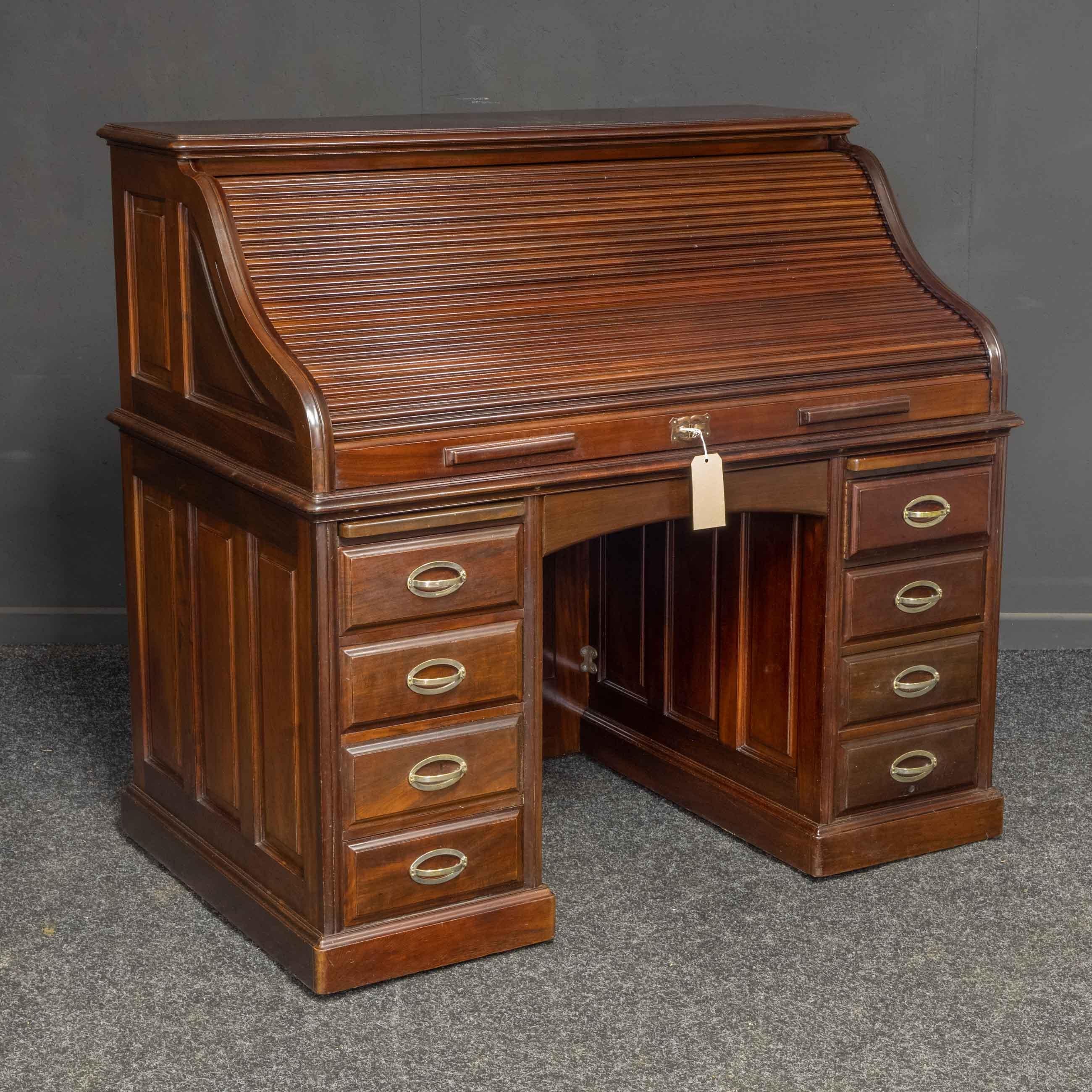 This is a fine quality antique mahogany roll top desk most likely made by Holland & Son or Maples. The satinwood veneered interior has many pigeon holes, and drawers plus two pen slides and two unusual finger pulls. The lock has been serviced and