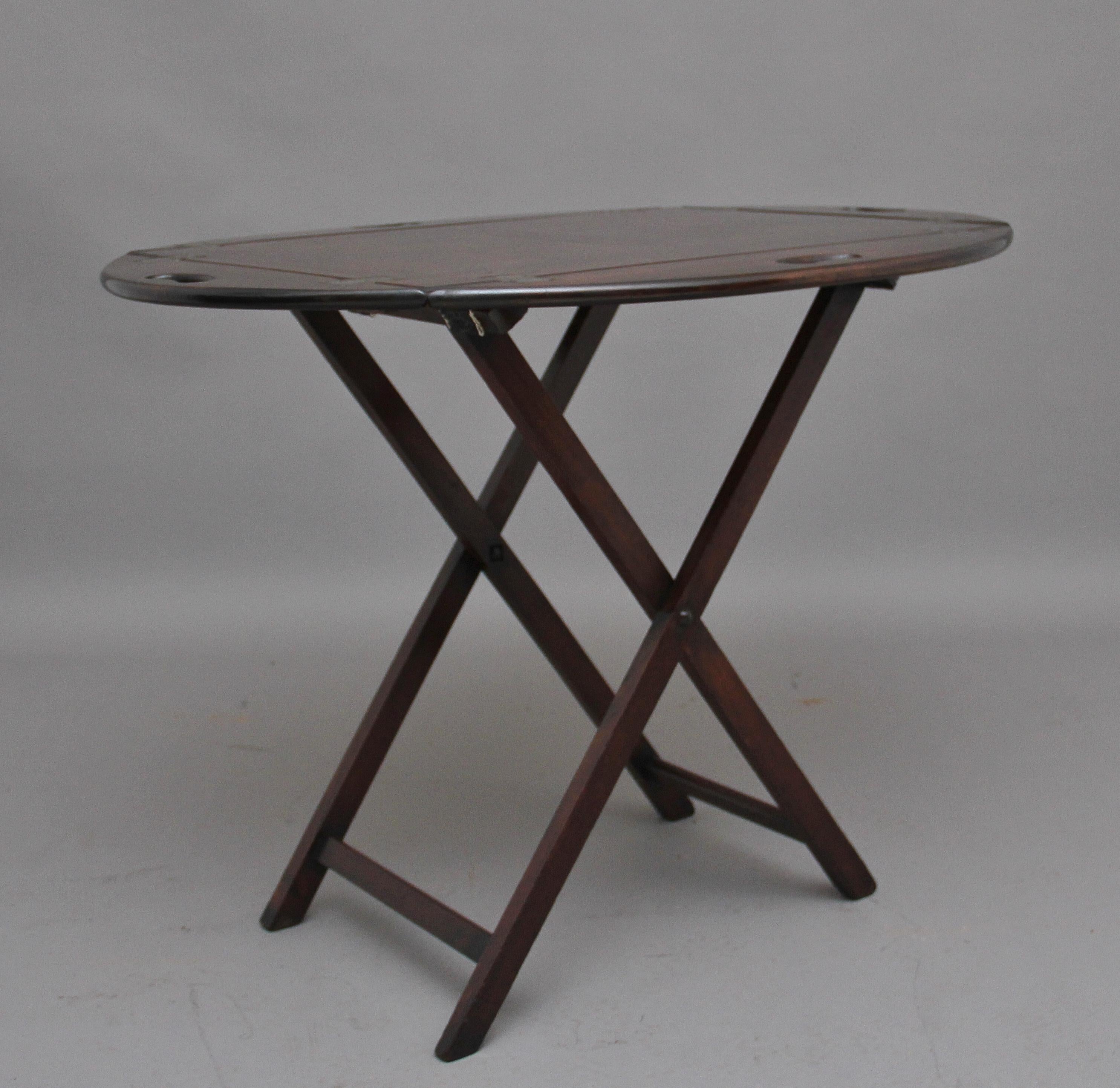 Early 20th century mahogany folding butlers tray on stand, the rectangular paneled tray has four folding sides with inset brass hinges with each side having fret cut carrying handles, supported on folding stand, circa 1920.
  