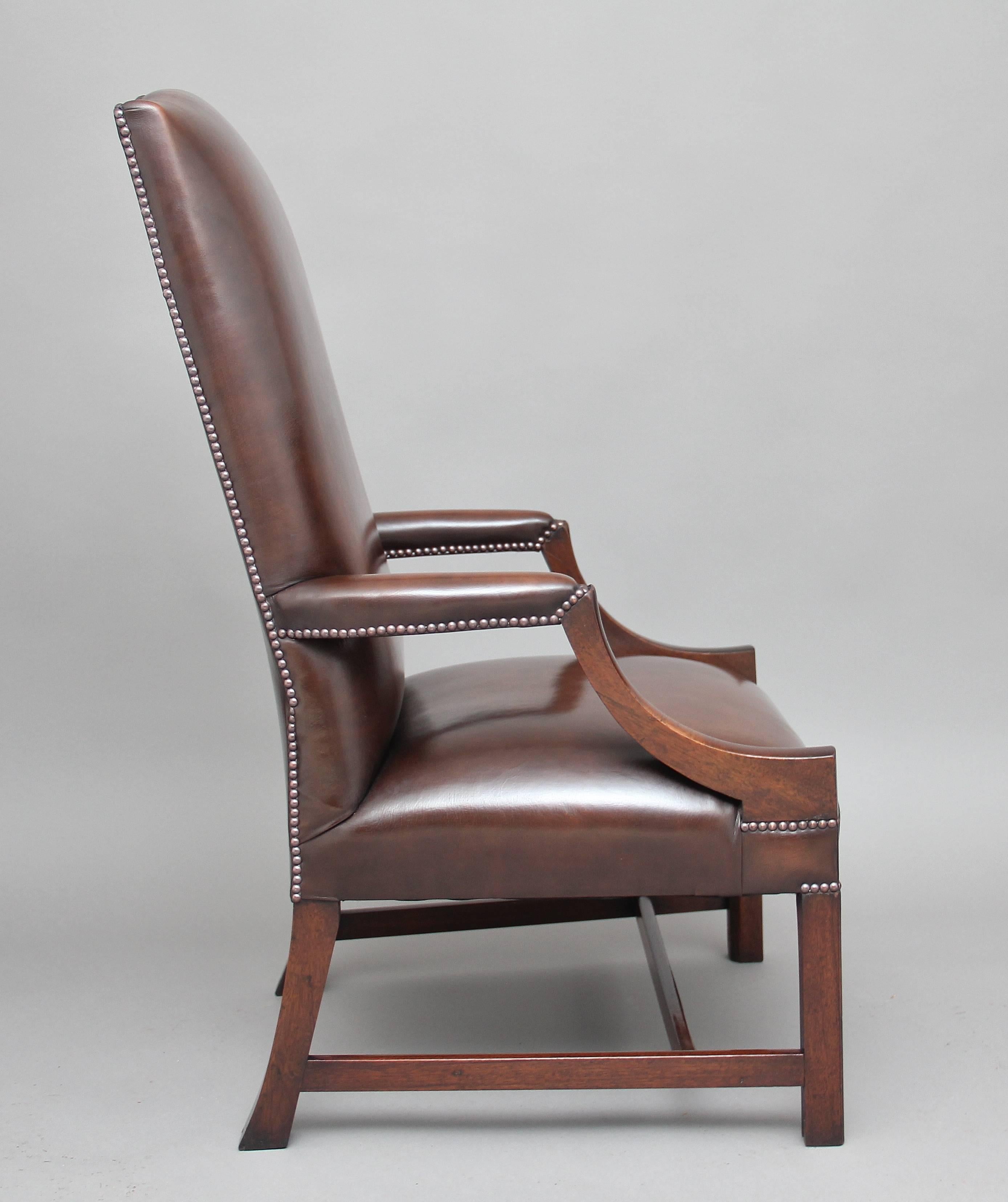 Early 20th century mahogany library chair upholstered in a brown leather, having a nice shaped high back with brass stud decoration, leather padded arms and shaped arm supports, standing on square legs united with side and front stretchers. Lovely