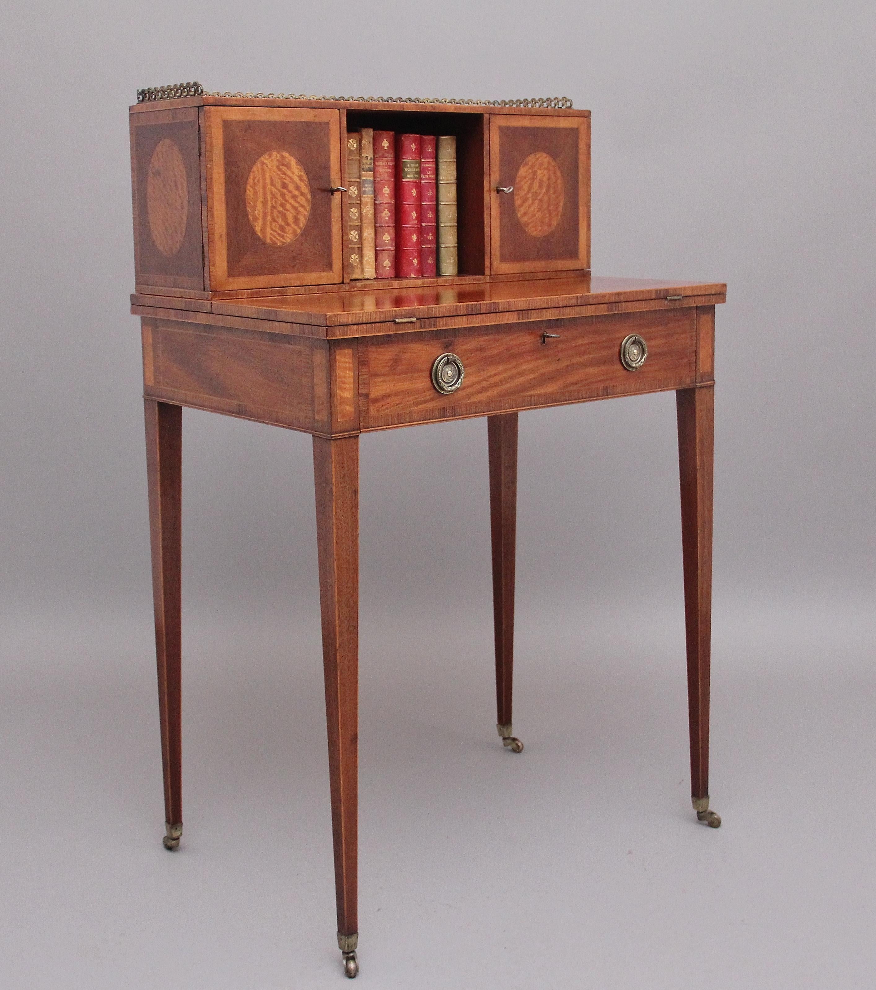 Early 20th Century mahogany & satinwood Boheur-Du-Jour / ladies writing table, the removable top structure having a pierced brass gallery above a central open cupboard, two cupboards either side with satinwood and tulipwood crossbanded doors and