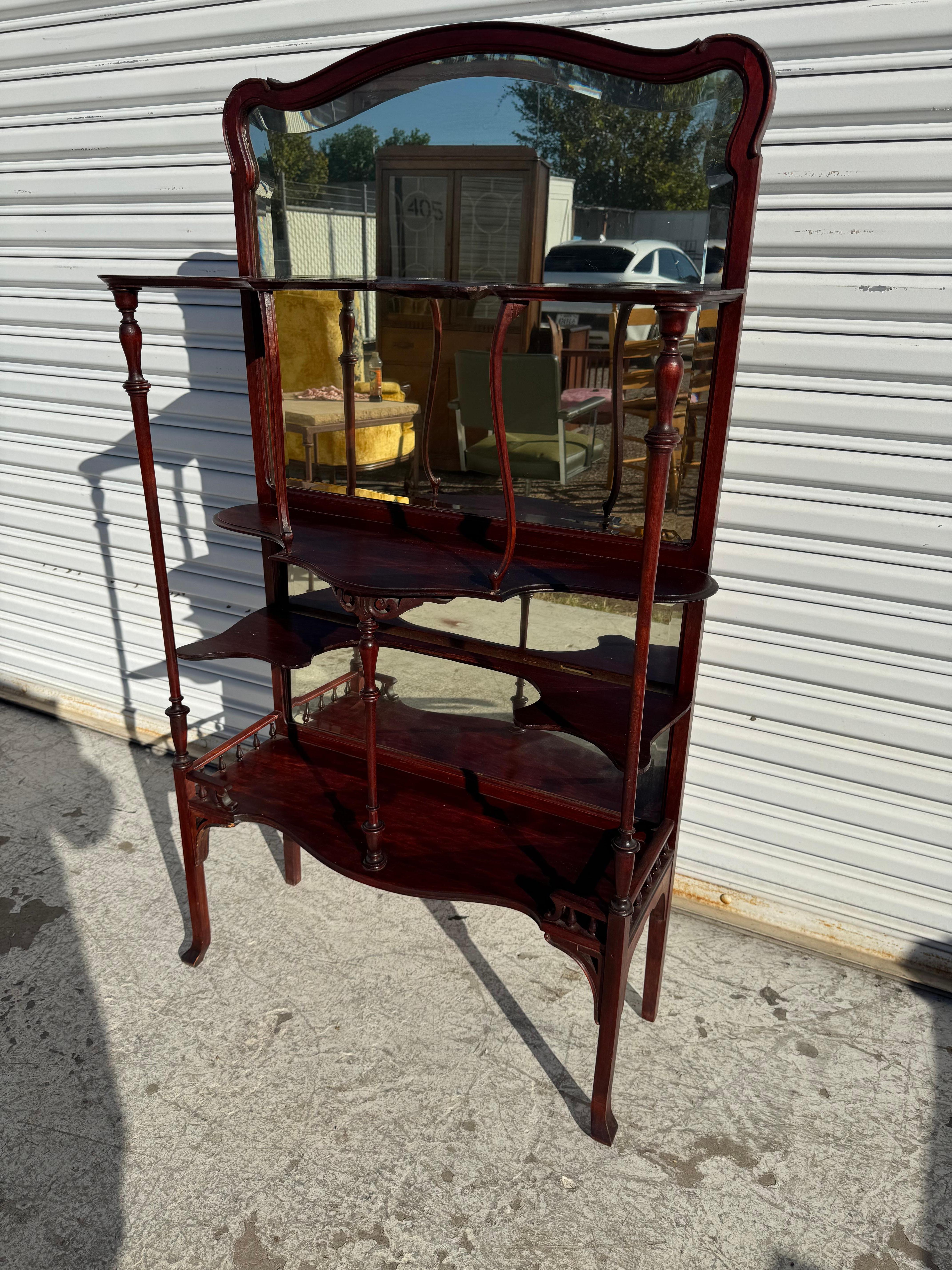 Si tratta di un'opera di pregevole fattura.
Questa etagere è realizzata in mogano. 
Ha uno schienale a specchio e gambe in stile cabriole.
Ci sono molti scaffali per avere un ampio spazio espositivo.