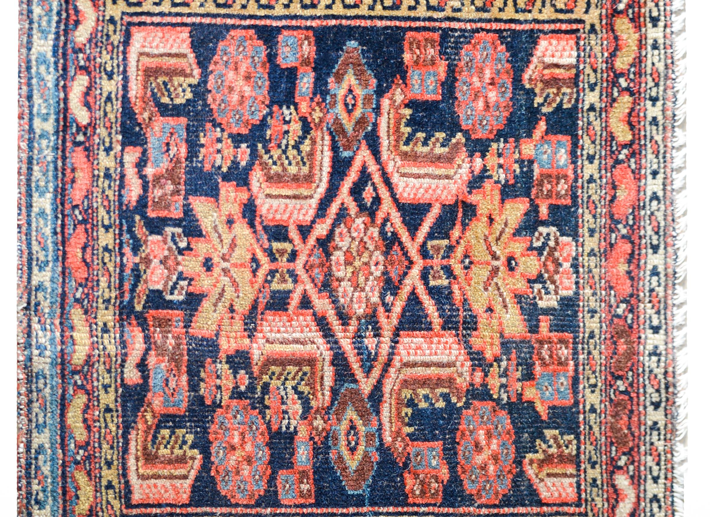 A wonderful early 20th century Persian Malayer bag face with a wonderful tribal pattern containing stylized flowers and leaves woven in pinks, crimsons, golds, and creams, against a dark indigo background. The border is expertly woven with multiple