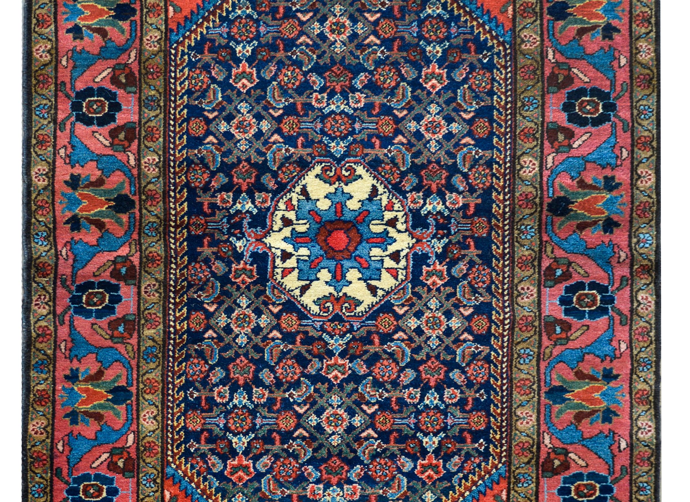 An wonderful early 20th century Persian Malayer Herati rug with a beautiful central stylized floral medallion amidst a field of stylized flowers and leaves woven in crimson, green, cream, and light and dark indigo, against a dark indigo background,