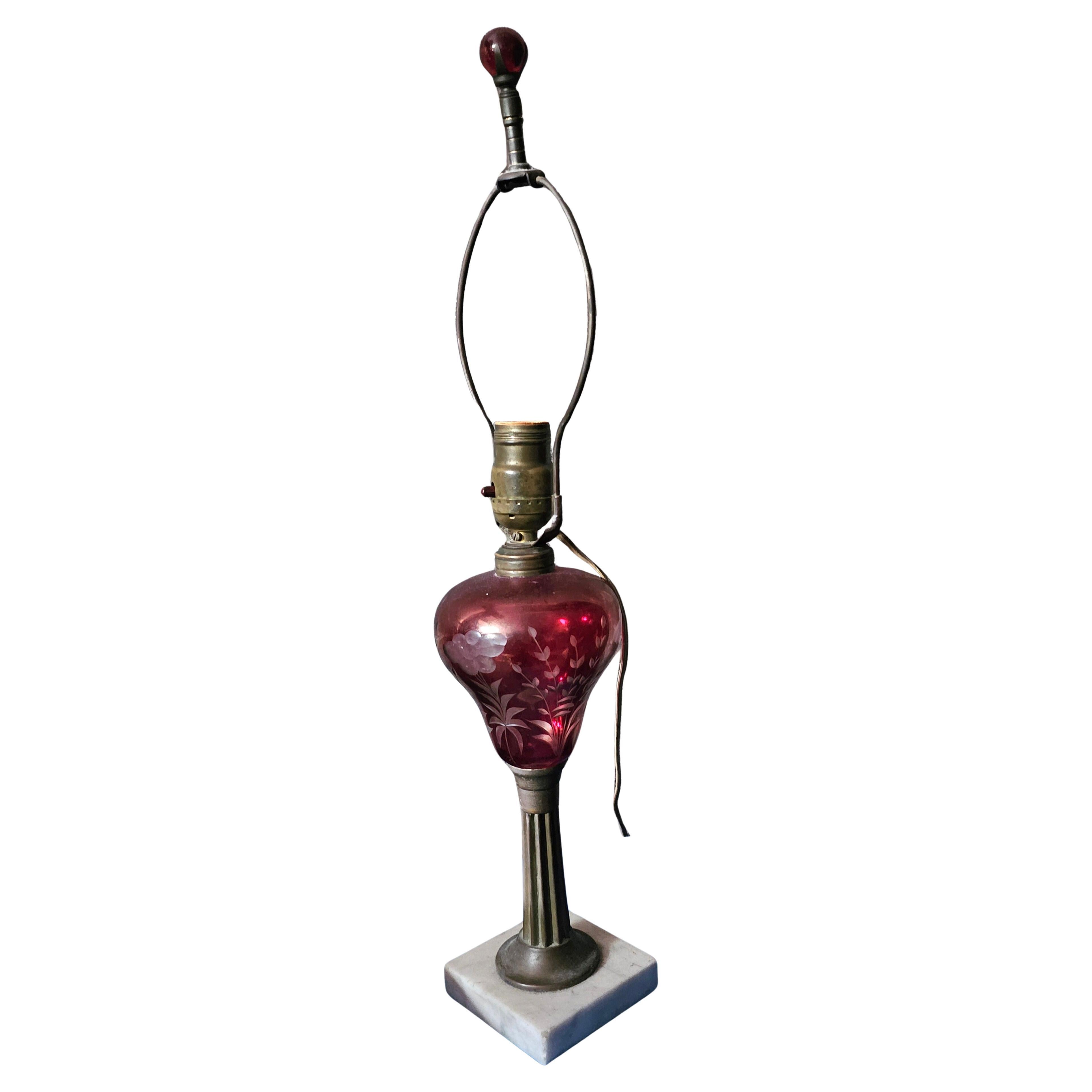 An Early 20th Century Marble and Cranberry Glass Table Lamp with original harp and finial.
Measures 4