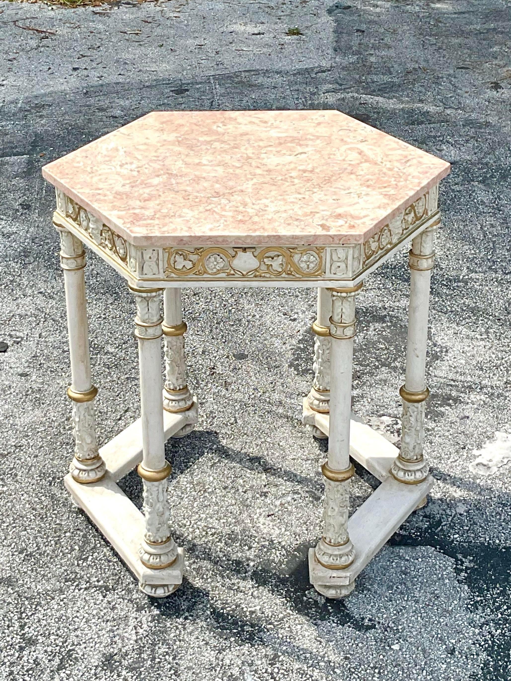 Opulent center or entry table in hexagon shape with a gorgeous rose colored marble top with an intricate carved painted base. The gilt adds an element of elegance and sophistication to elevate any entry or hall corridor. Acquired from a Palm Beach