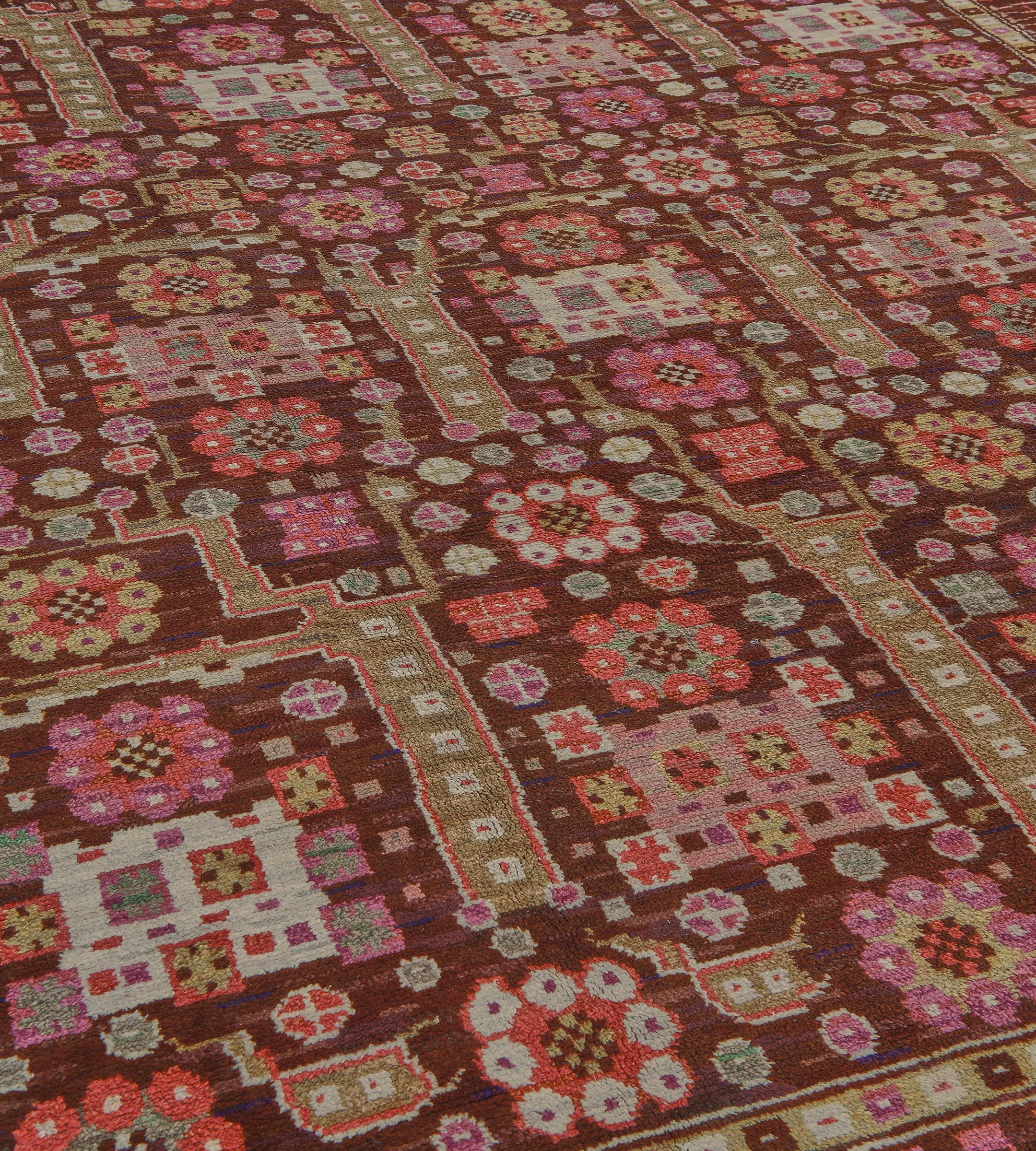 Dieser traditionelle handgewebte schwedische Teppich hat ein schattiertes schokoladenbraunes Feld mit stilisierten Rosettenanhängern und kühnen Halmen, die ein weiteres Blumenmotiv in einer schattierten korallenroten Mäanderbordüre zwischen