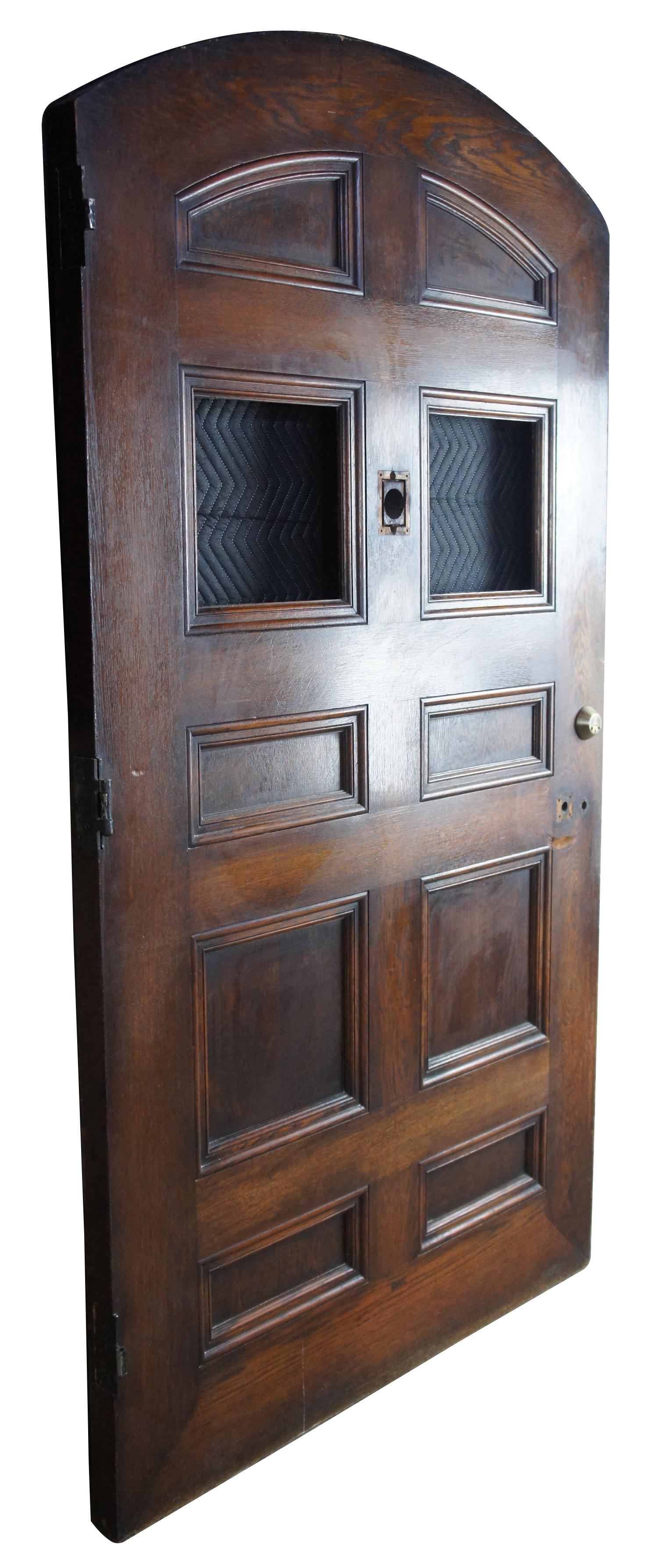 This massive arched solid oak door comes from one of the first homes built in oakwood, Ohio by Harry I Schenck. It is the original front door, circa early 1900s. Features eight panels and two square inserts for leaded, stained or art glass. A nice