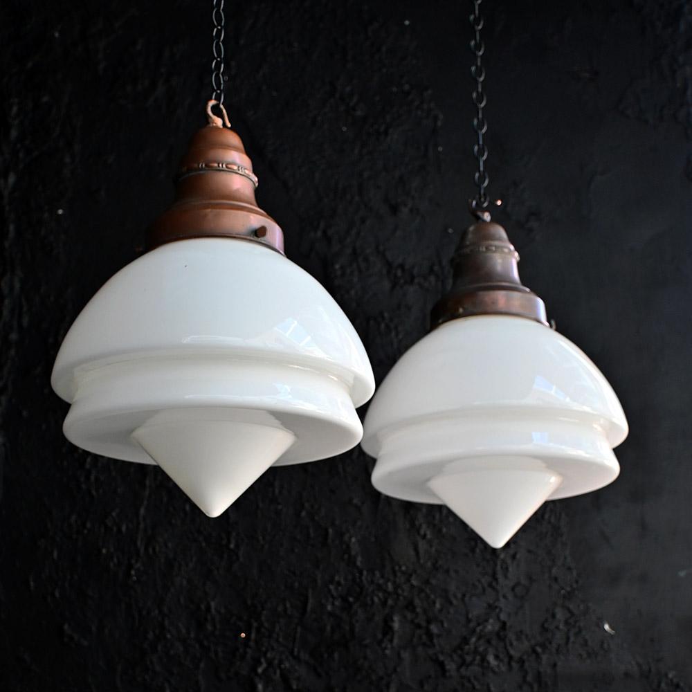 Early 20th Century Matched Pair of Milk Glass Art Deco Light Pendants 
A highly decorative and unusual shaped matched pair of milk glass light pendants. Art deco in style and of a classic design shape. The gallery is stamped Siemens, these lights