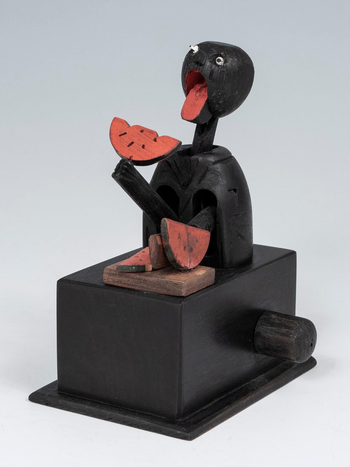 Early 20th century mechanical toy from Kobe, Japan.

This small mechanical toy was made in Kobe, Japan. This is the classic doll of a man chopping and eating a slice of watermelon, with the action controlled by a turning knob on the left side,