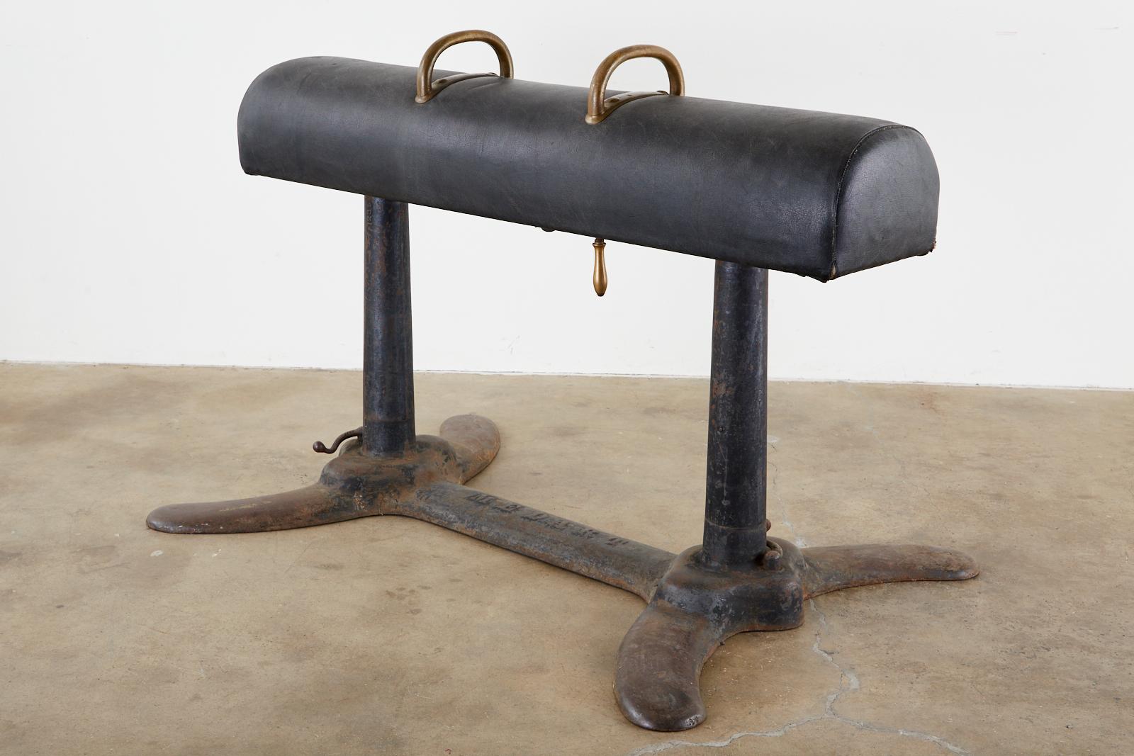 Rare early 20th century industrial style pommel horse made by Medart manufacturing company of St. Louis, Missouri. Large cast iron frame with adjustable features for use in a gymnasium. The body is covered with a Naugahyde leatherette and topped