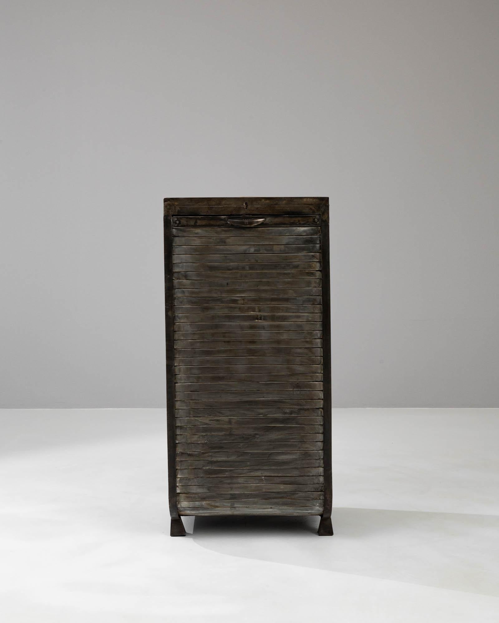 This Early 20th Century Metal Cabinet is a masterpiece of industrial design that fuses functionality with raw aesthetic appeal. Its solid metal construction stands as a testament to the era's craftsmanship, with a distinct patina that tells a rich