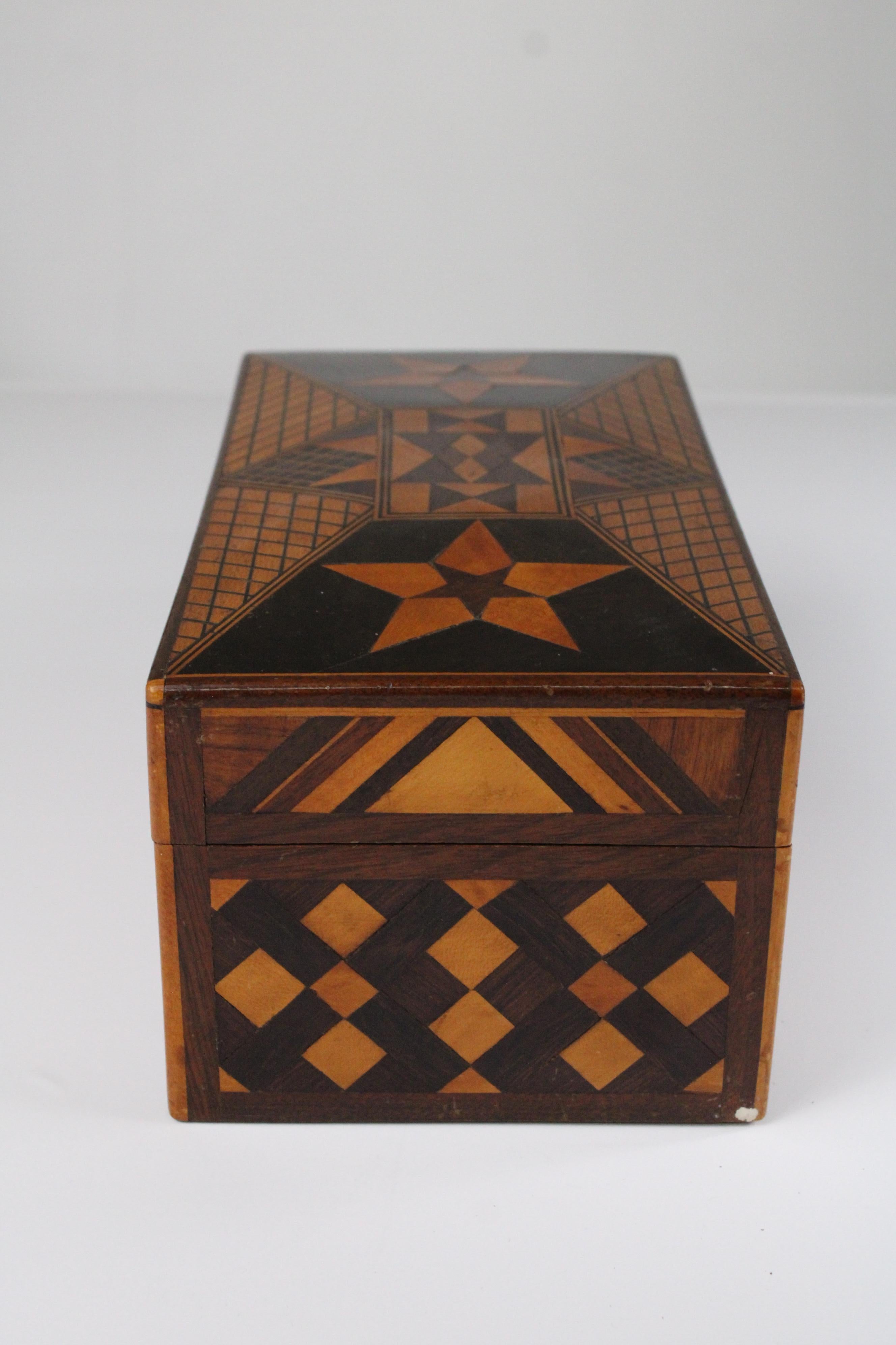 Este exquisito buzón, fabricado en Puebla, México, a principios del siglo XX, es un testimonio de la rica tradición de marquetería de la región. Fabricada en madera de frutal, la caja presenta intrincadas incrustaciones en toda su superficie. Los