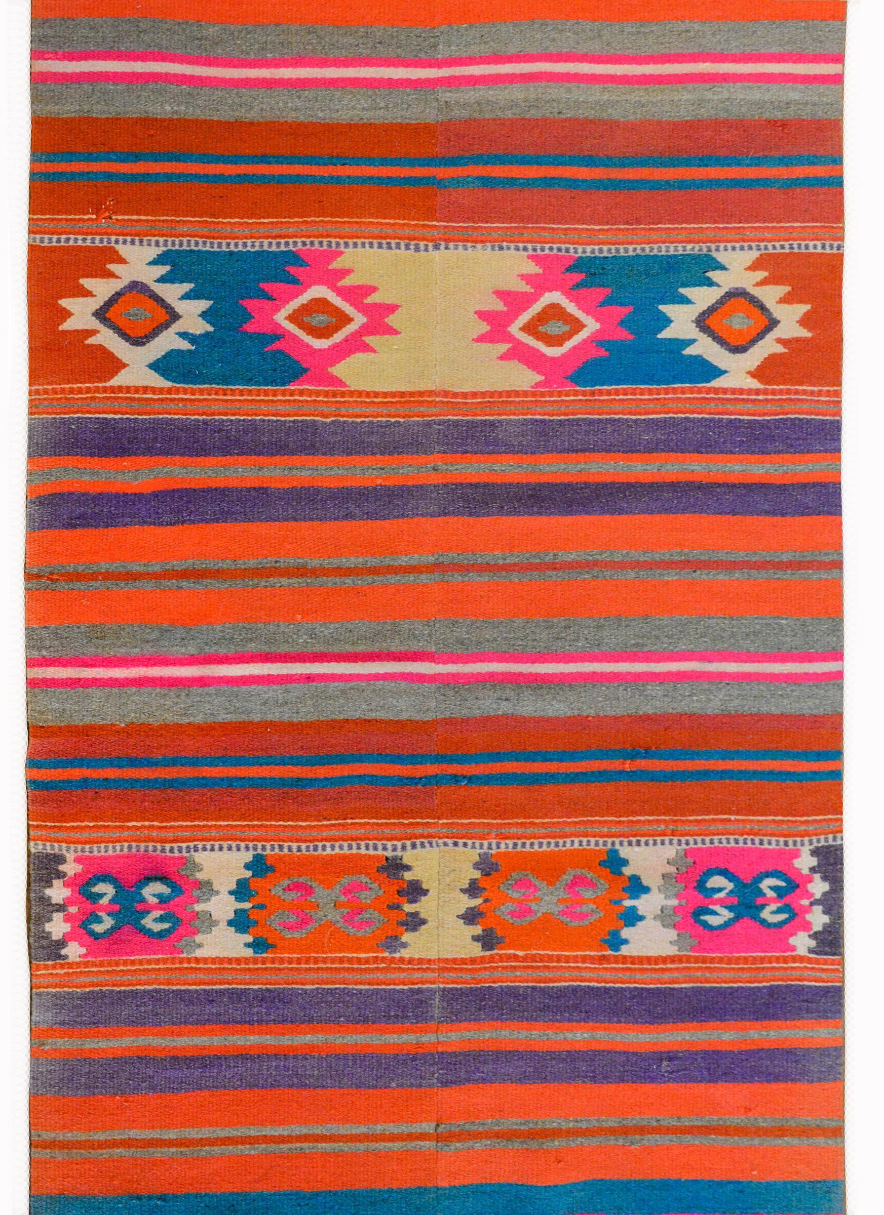 A gorgeous and bold Late 20th century Mexican handwoven kilim rug with rich orange, indigo, crimson, pink, white, and natural wool stripes, and three geometric patterned stripes.