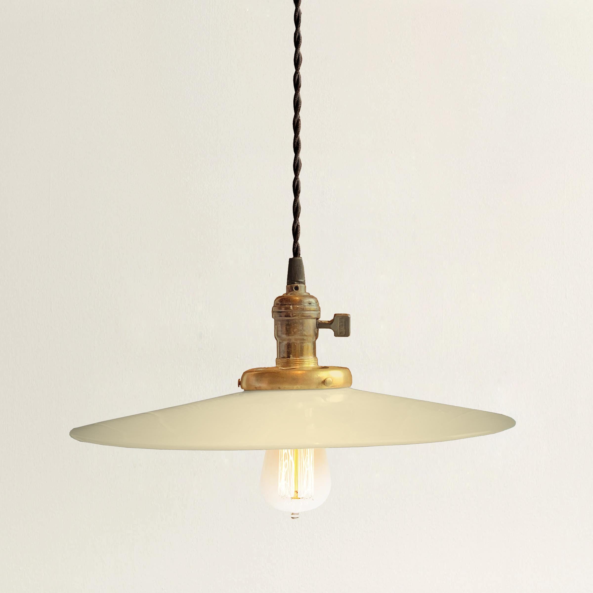 A simple yet chic early 20th century American pendant light fixture with a wide flat milk glass shade and an unlacquered brass fitting and a new twisted black silk cord that's adjustable up to 10 feet in length. Fixture is currently wired with a