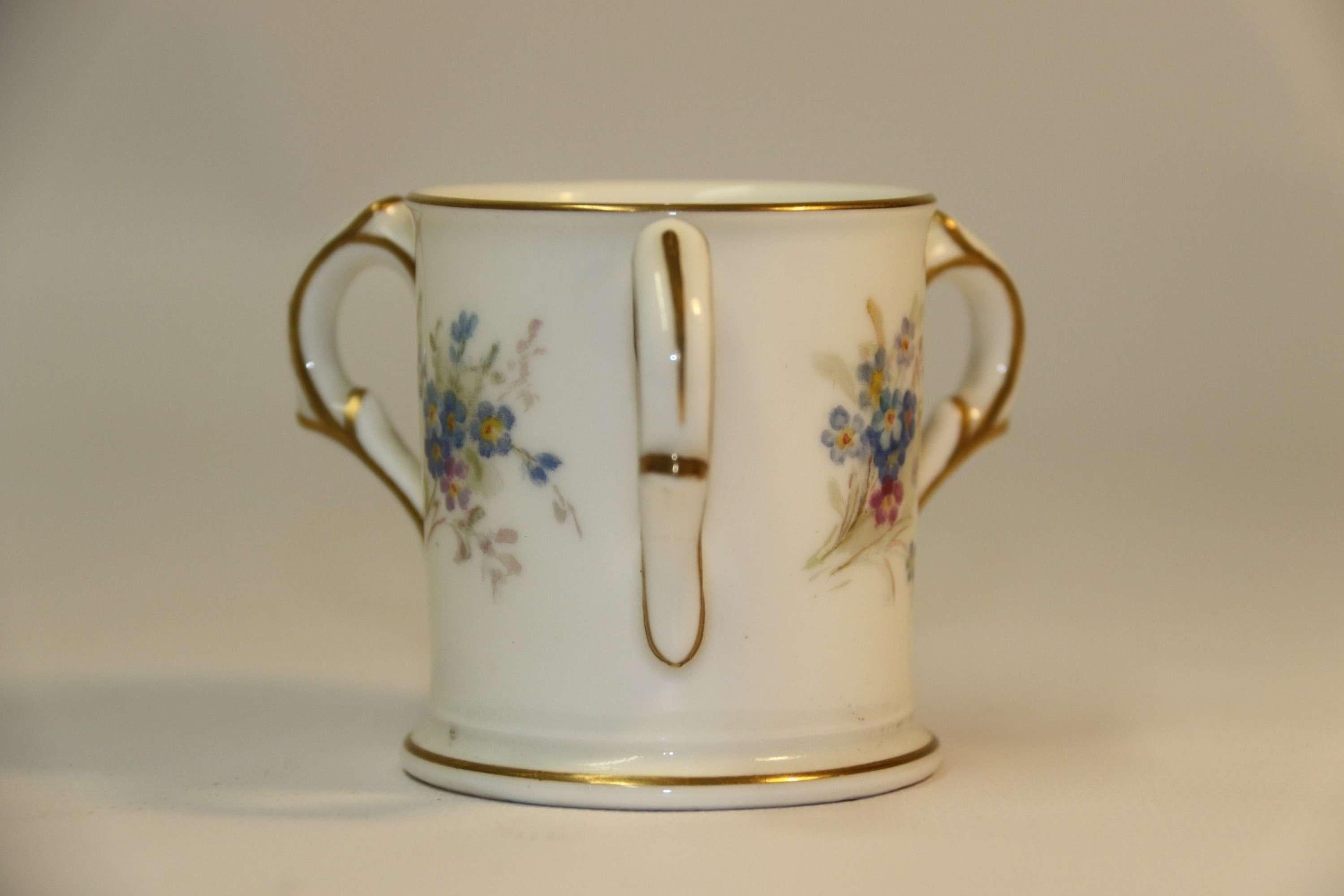 A Miniature Royal Worcester porcelain loving cup

This delightful early 20th century Royal Worcester porcelain miniature loving cup has a white ground with fabulous hand painted sprays of forget-me-nots. These are centralised between the three