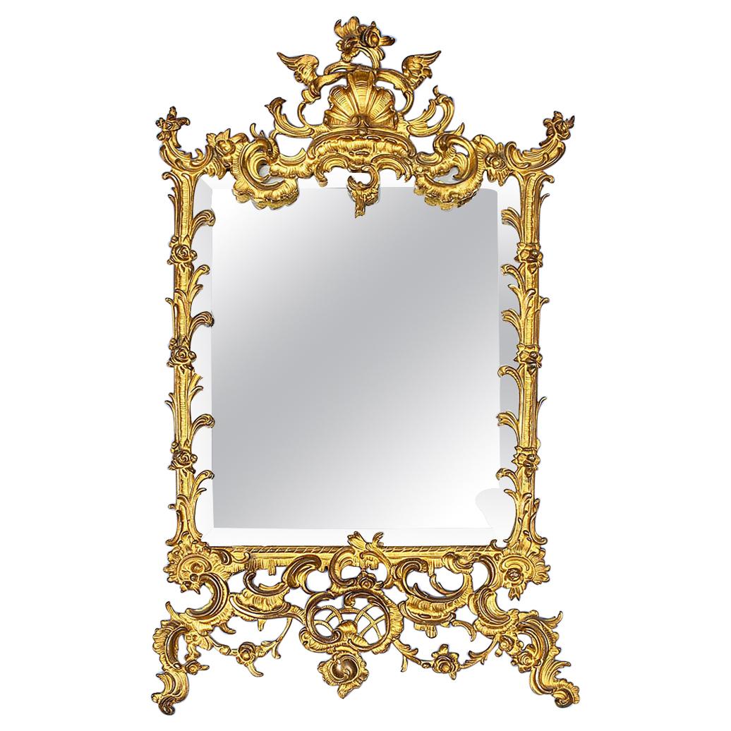 Early 20th century mirror in brass openwork frame
A mirror in a brass openwork frame with decorations in the form of shells, flower buds, wings and rocaille. The mirror pane is bevelled with slight flaws of silver paint on the inside. On the back