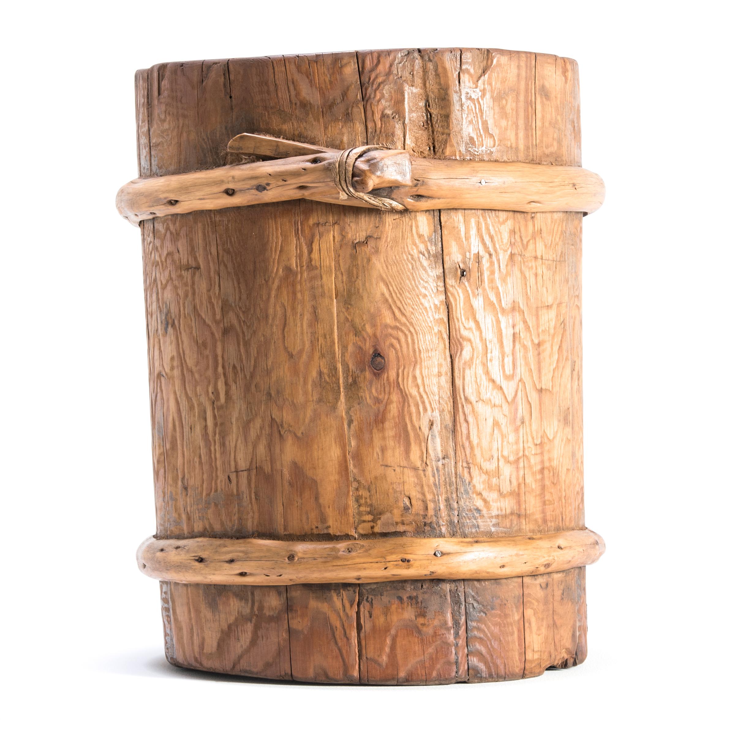 This beautiful grain container was made over a century ago in Mongolia. It was made to last: the sturdy pine wood slats tightly joined, with the forever knots helping to secure them in place. The container shows some signs of wear that attest to its