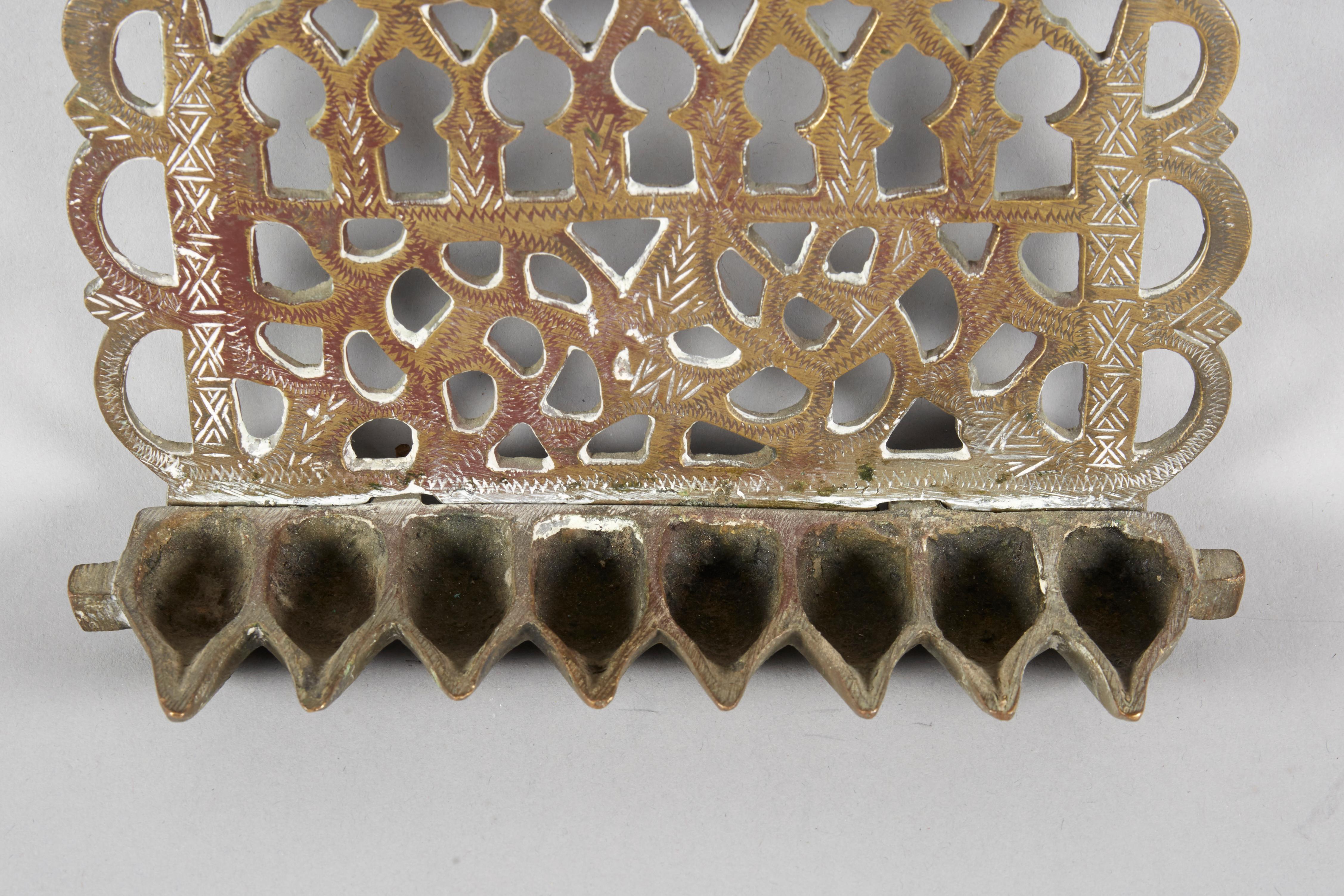 Hängende Chanukka-Lampe Menora aus Messing, Marokko, um 1900. 
Durchbrochene Verzierungen, Gravuren und Vogeldarstellungen auf beiden Seiten.
Die Rückplatte aus schwerem Messingguss ist durchbrochen und mit Blattranken und einer Reihe von acht